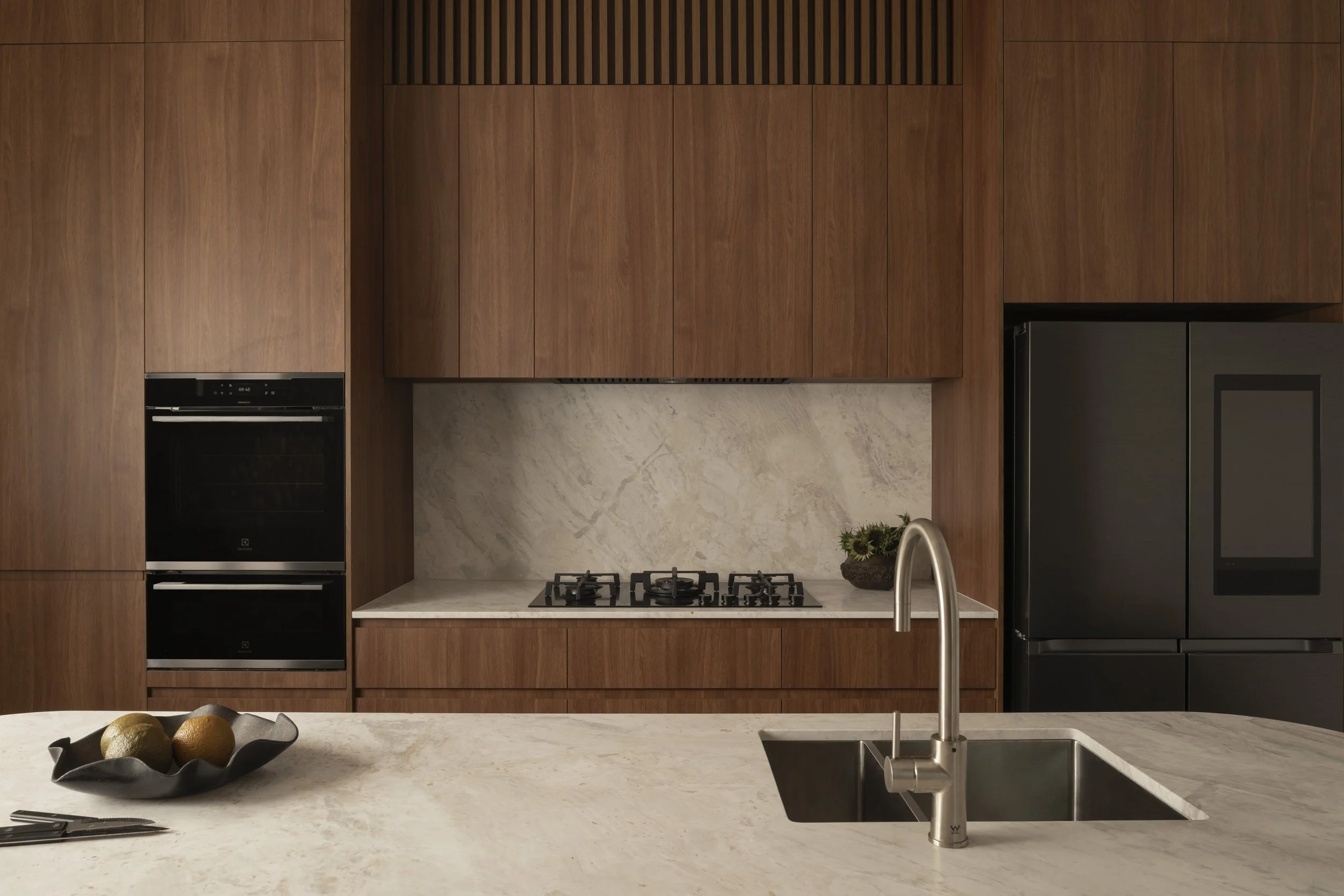 Oakover St – Custom kitchen with warm timber cabinetry, stone benchtops, integrated appliances, and minimalist detailing