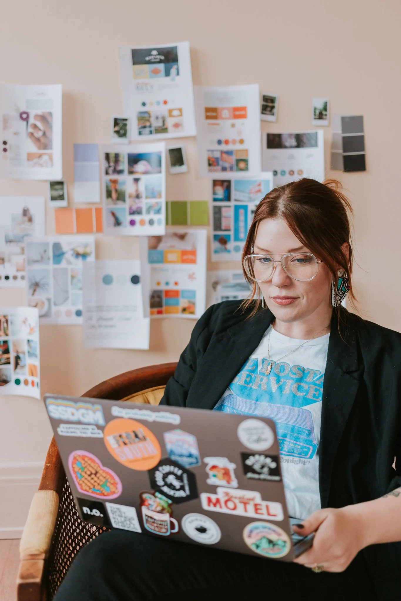 Person sitting on bed working on a laptop, holding a cup of coffee with latte art in one hand.