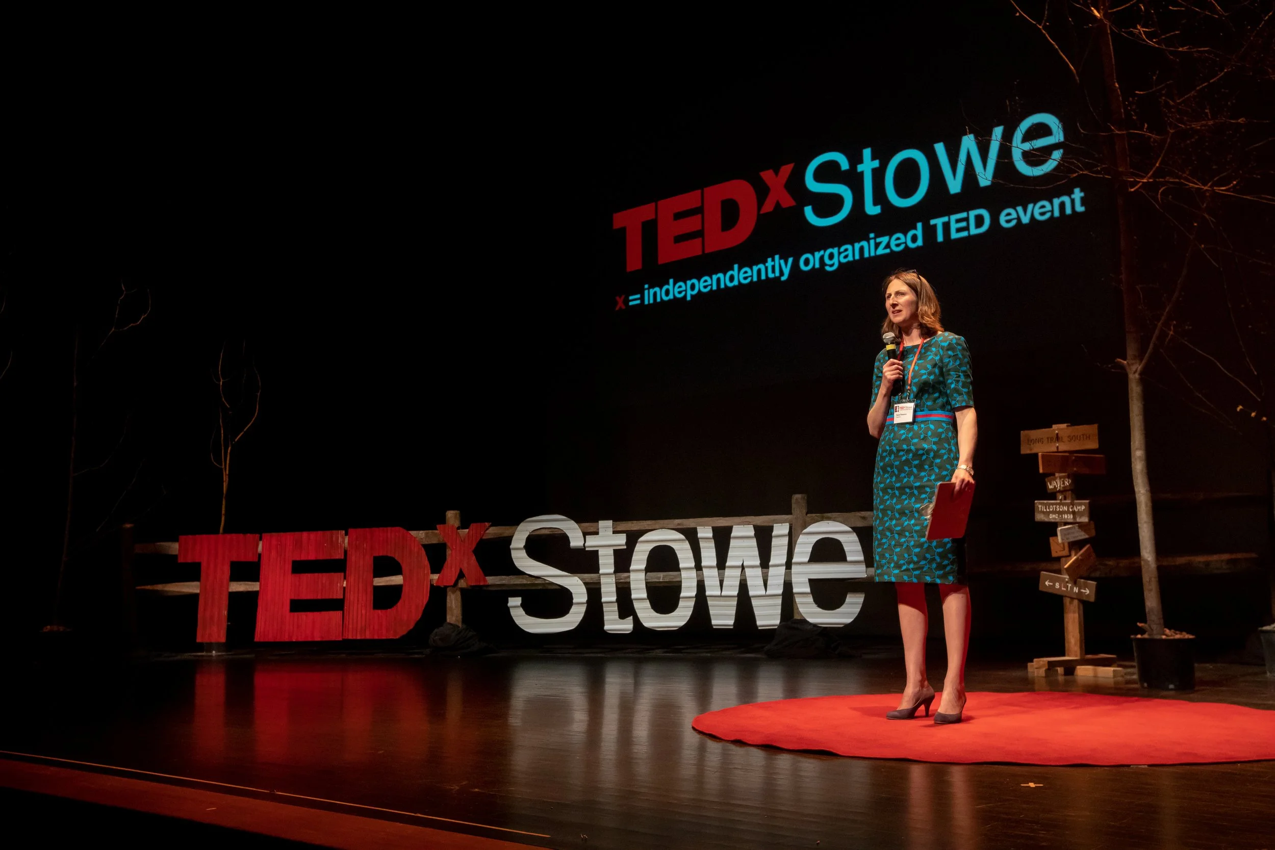 Tessa Rawson standing on stage at a TEDx event. She has been a TEDx organizer and coach for 12 years.
