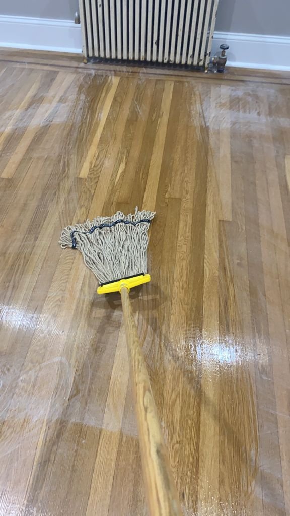 Cleaning a wet hardwood floor with a mop.