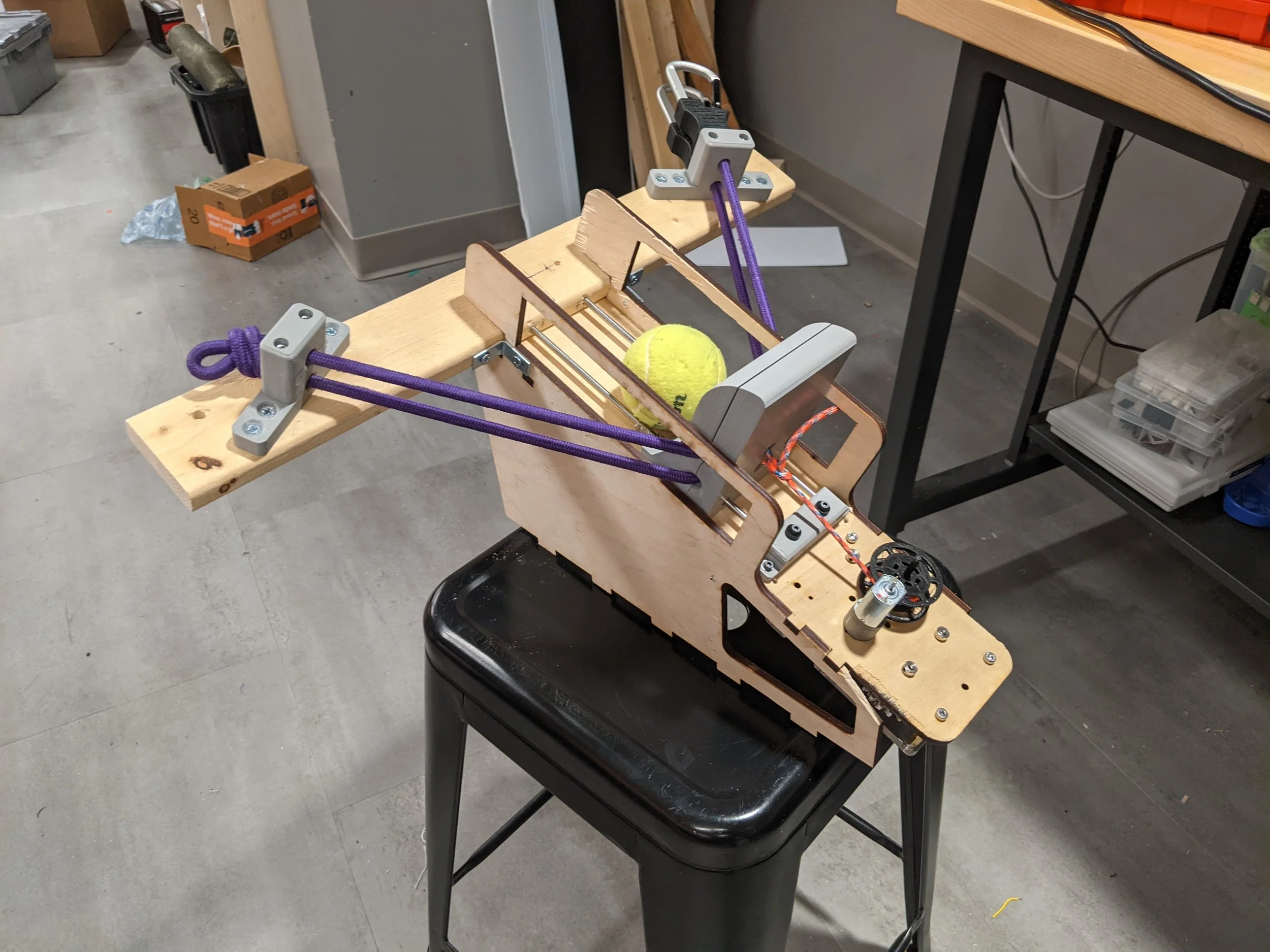 The launching assembly loaded with a tennis ball. Note the non-destructive use of a bungee cord, the multiple 3-D printed parts with heat-set inserts, and "off-label" use of preexisting hardware (including a mismatched allen key as a driveshaft)