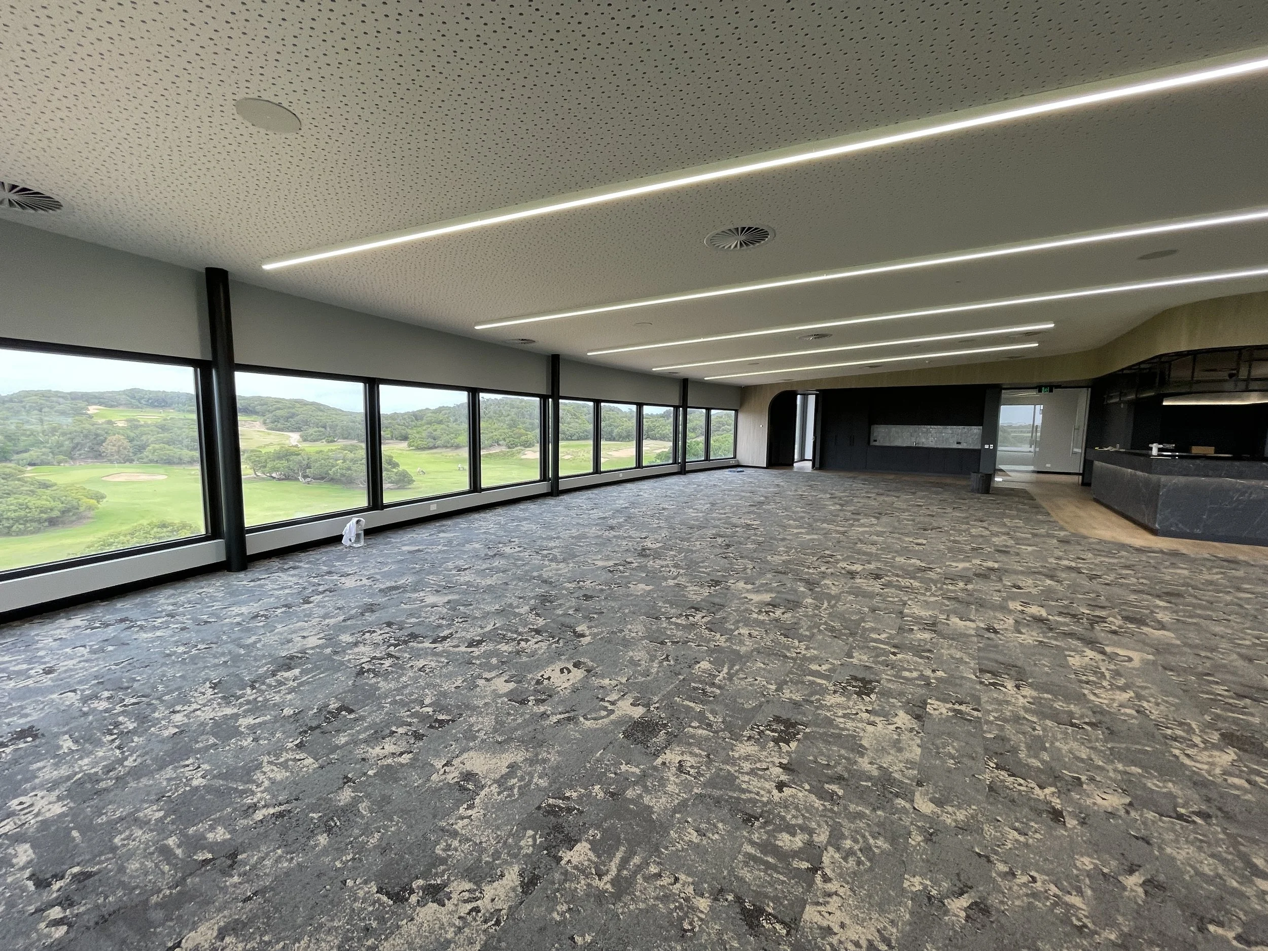 Empty spacious room with large windows overlooking a golf course