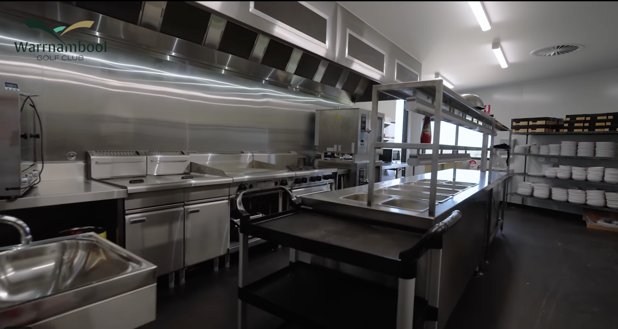 Empty commercial kitchen with stainless steel appliances, shelves, and plates at Warrnambool Golf Club.