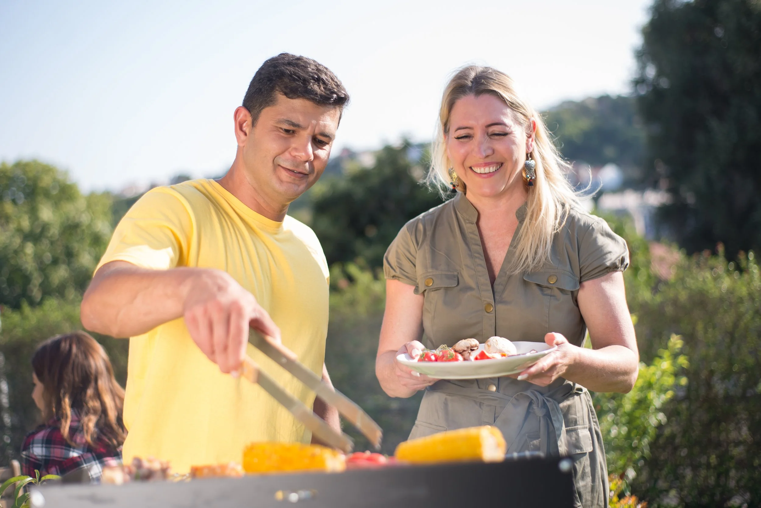 A couple enjoy cooking a BBQ outside in the sunshine in Warrnambool Summer.