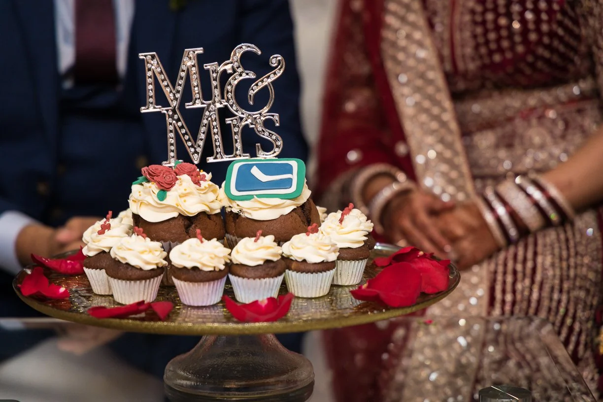 Wedding cupcakes with 'Mr & Mrs' topper and rose petals on a tray.