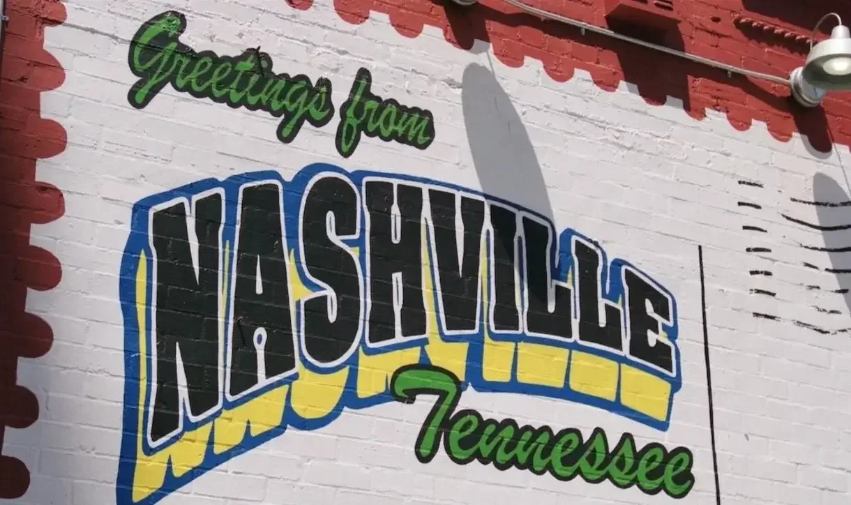 A mural on a brick wall reading "Greetings from Nashville Tennessee" with colorful stylized text and design.
