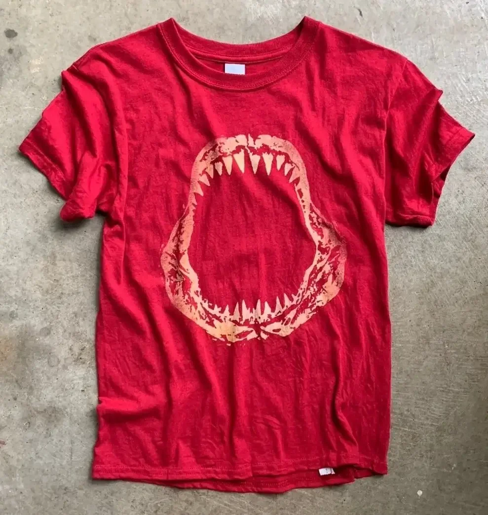 A red T-shirt with a graphic of a wide-open mouth with sharp teeth in the center.
