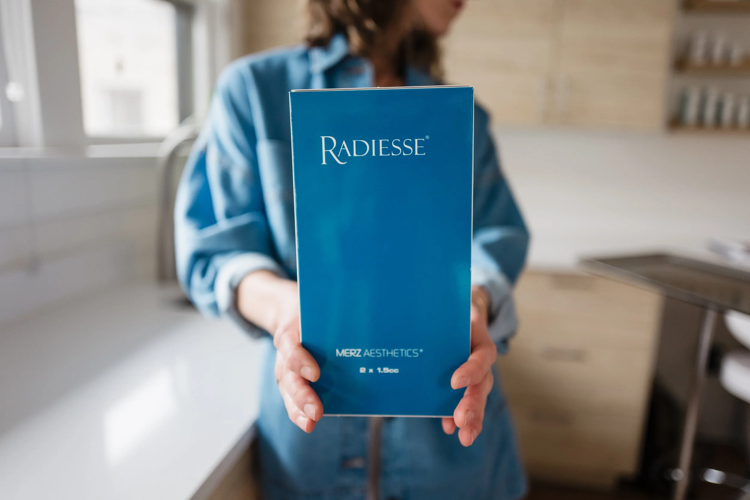 Person holding a box of Radiesse dermal filler