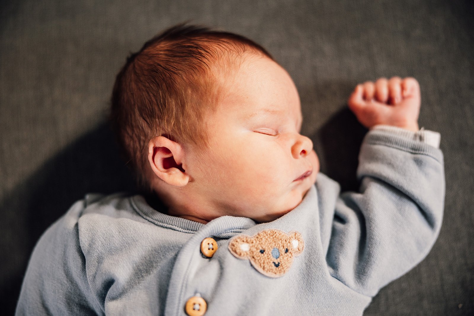 Sleeping baby wearing a blue outfit with a bear patch.