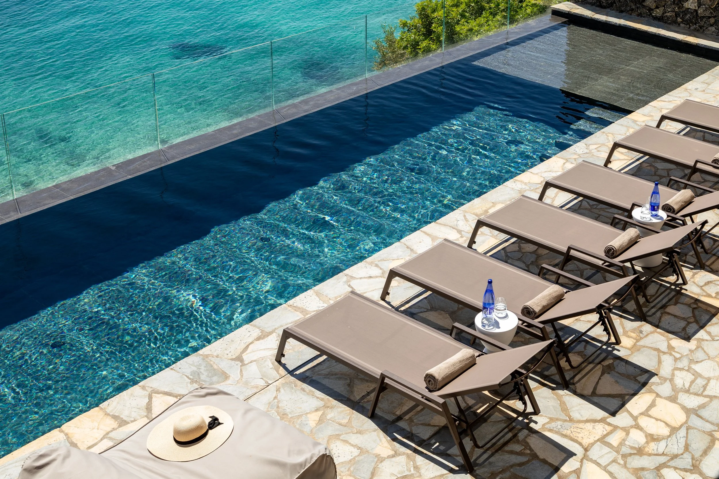 infinity pool overlooking the sea, sunbeds, summer hat and shades of blues