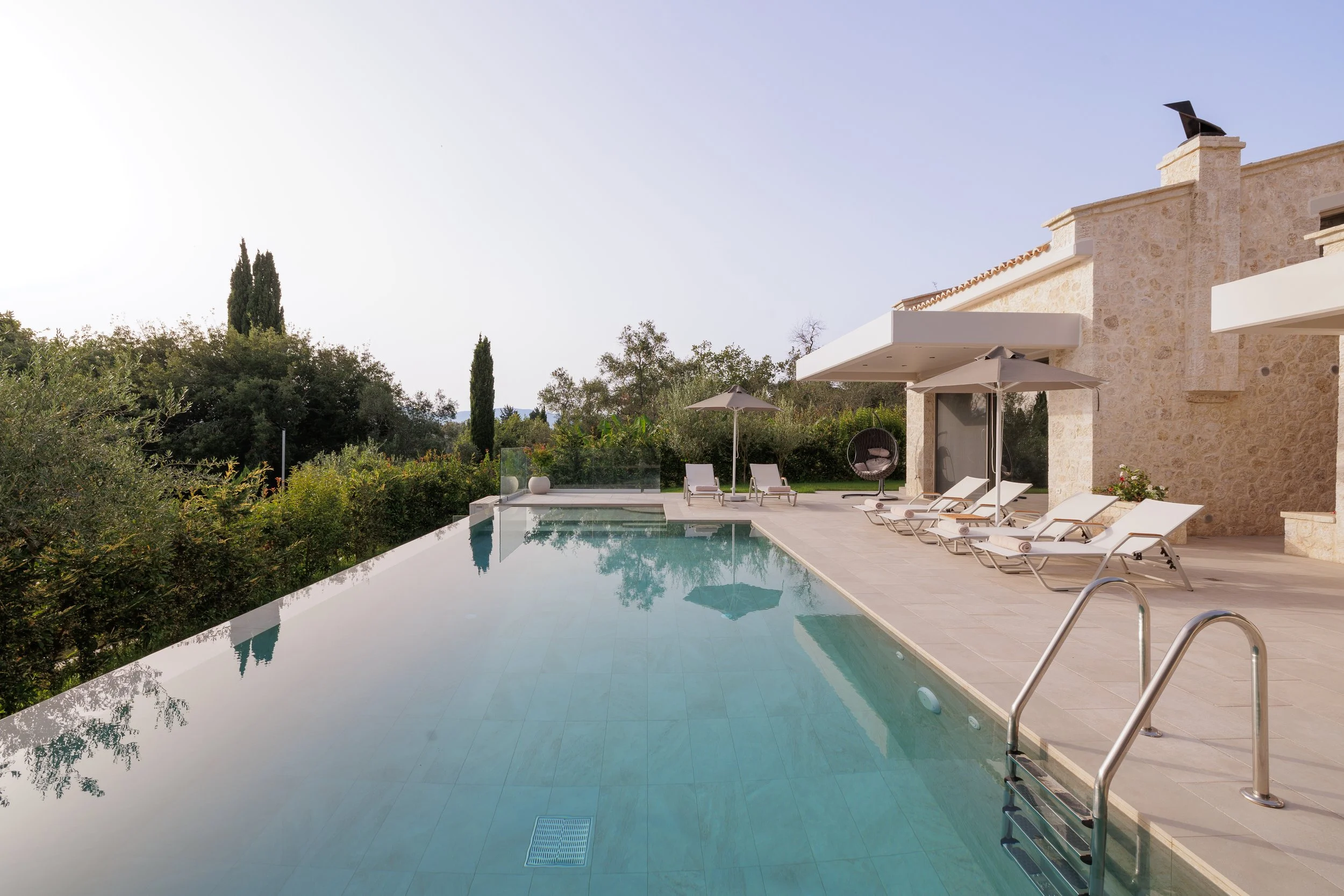 Private Swimming pool, sunbeds, greenery in a private villa.