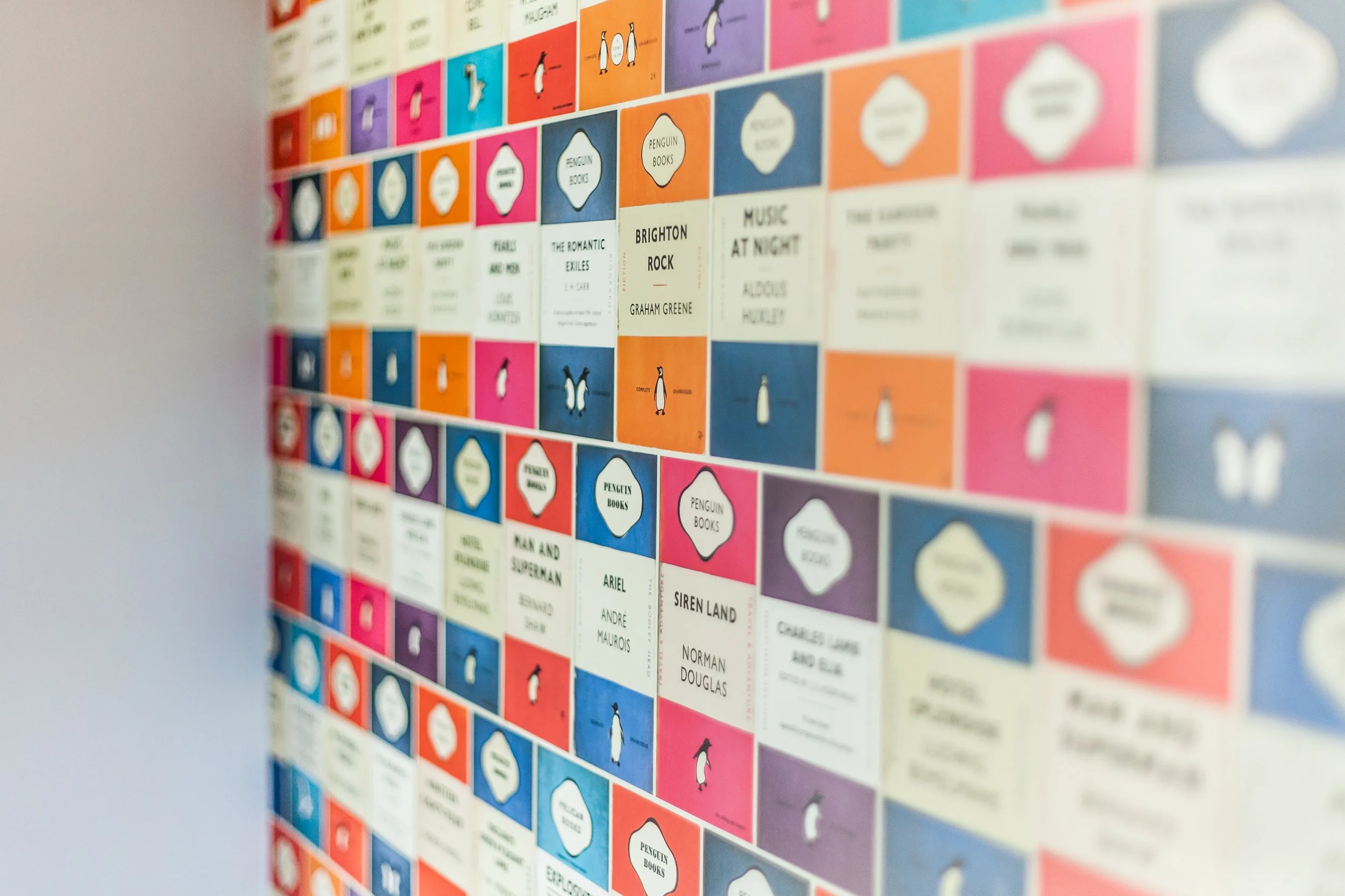 Colorful wall display of book covers, featuring penguin books, arranged in a grid pattern.