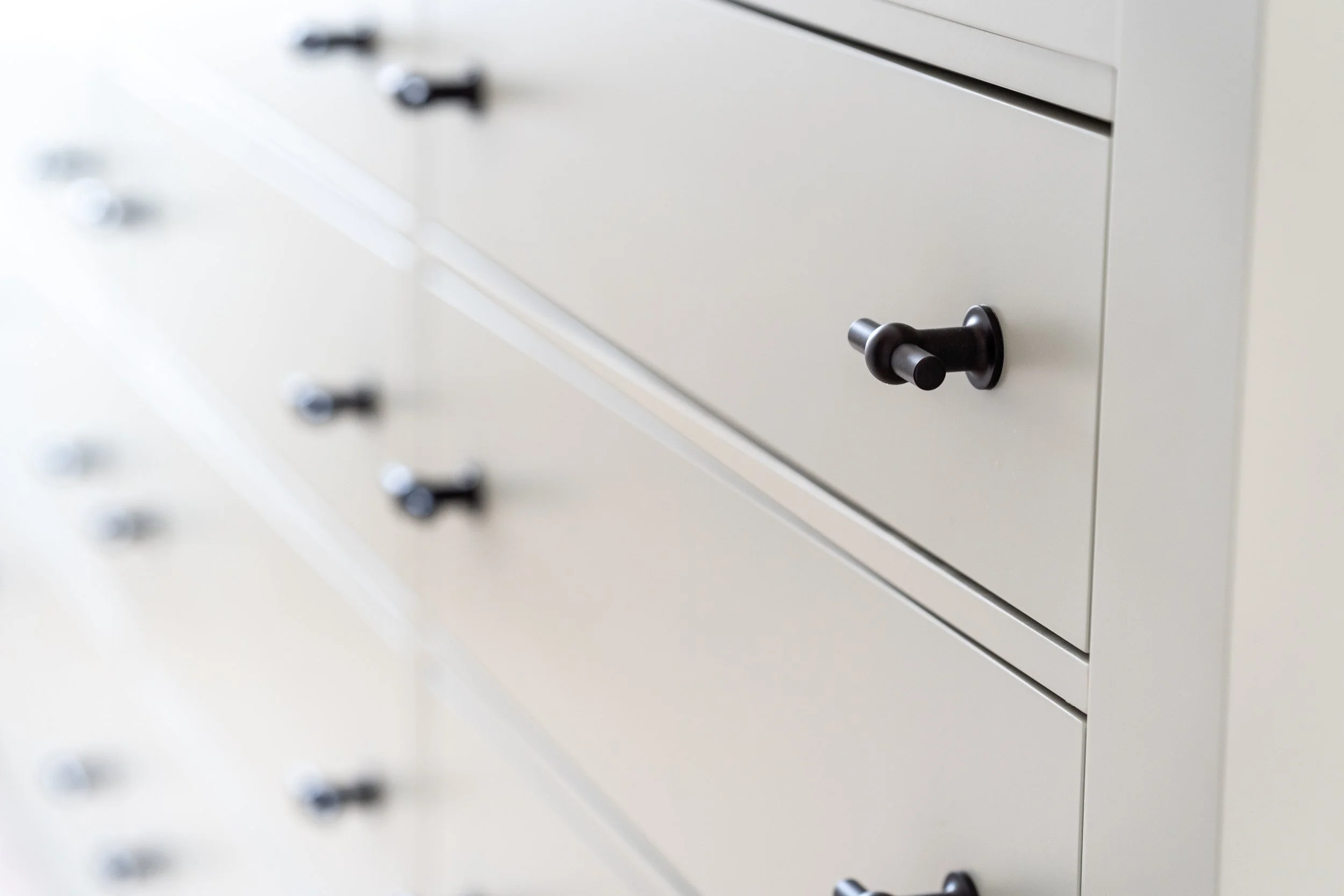 Close-up of beige filing cabinet drawers with black handles.