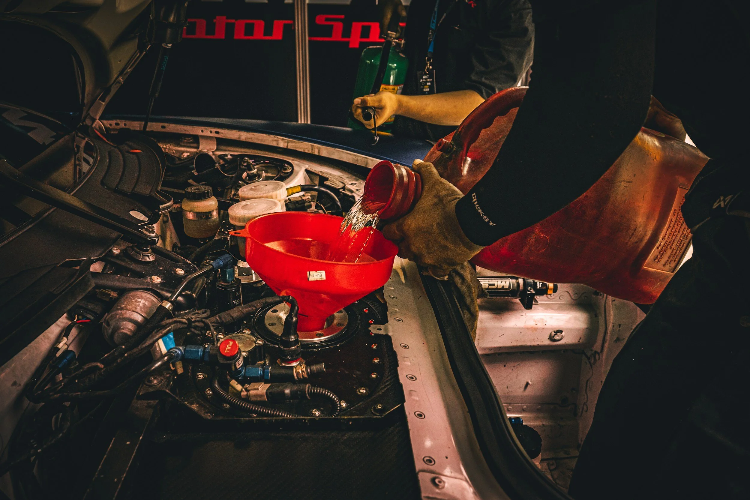 Engine oil being topped up through a red funnel during an HGV oil and filter change