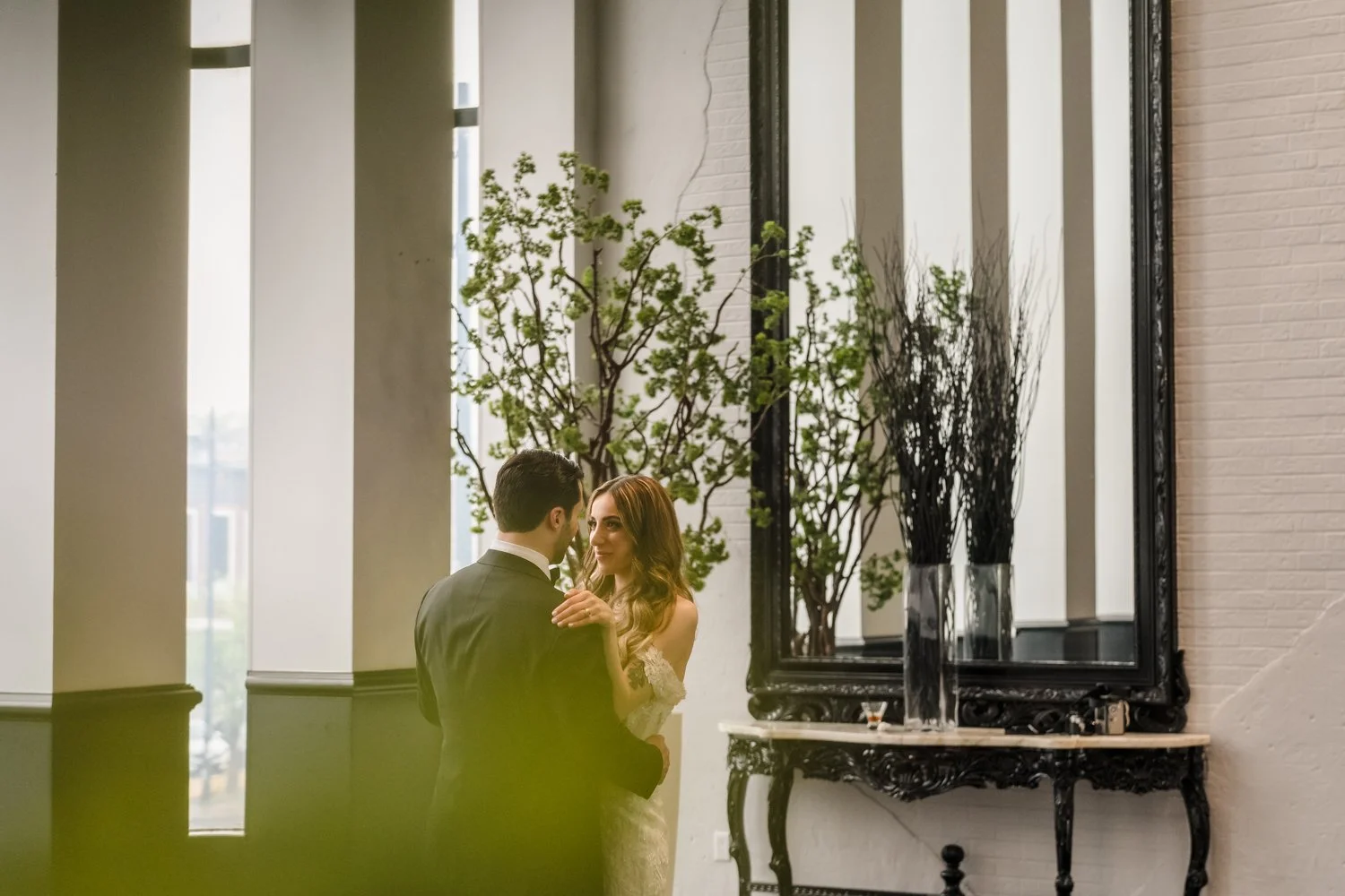 Bride and groom sharing a romantic moment inside Plaza Antique Montreal, framed by elegant mirrors, tall windows, and natural light during their wedding portraits.