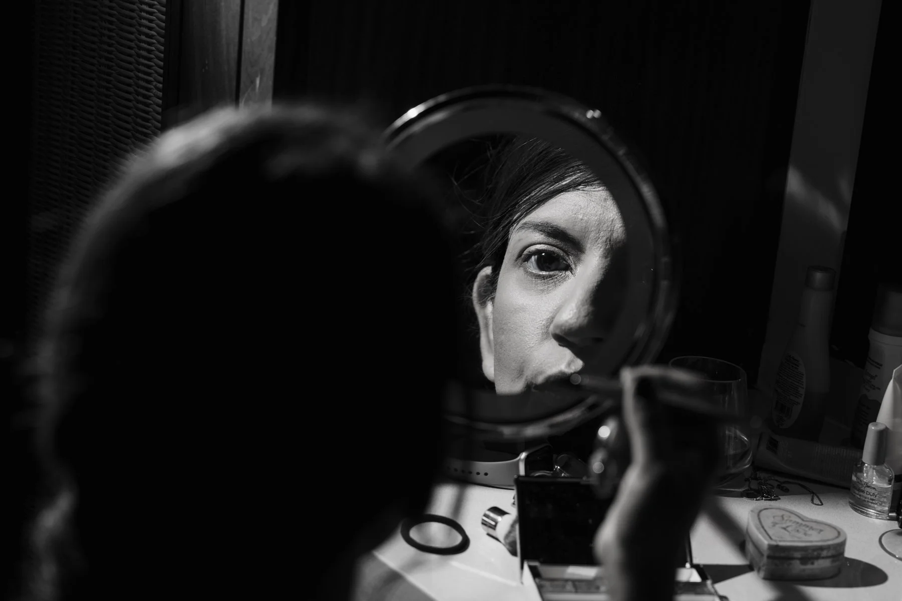 Black and white portrait of a bride reflected in a mirror while getting ready for her wedding in Mauritius.