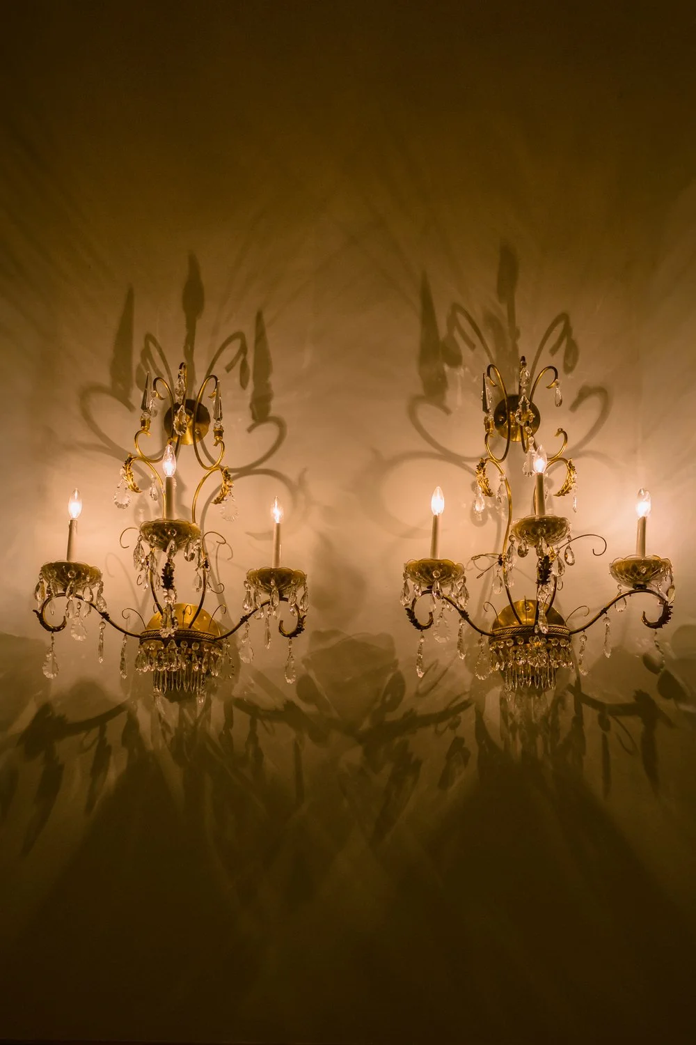 Crystal wall sconces casting dramatic shadows inside an elegant Montreal wedding venue.