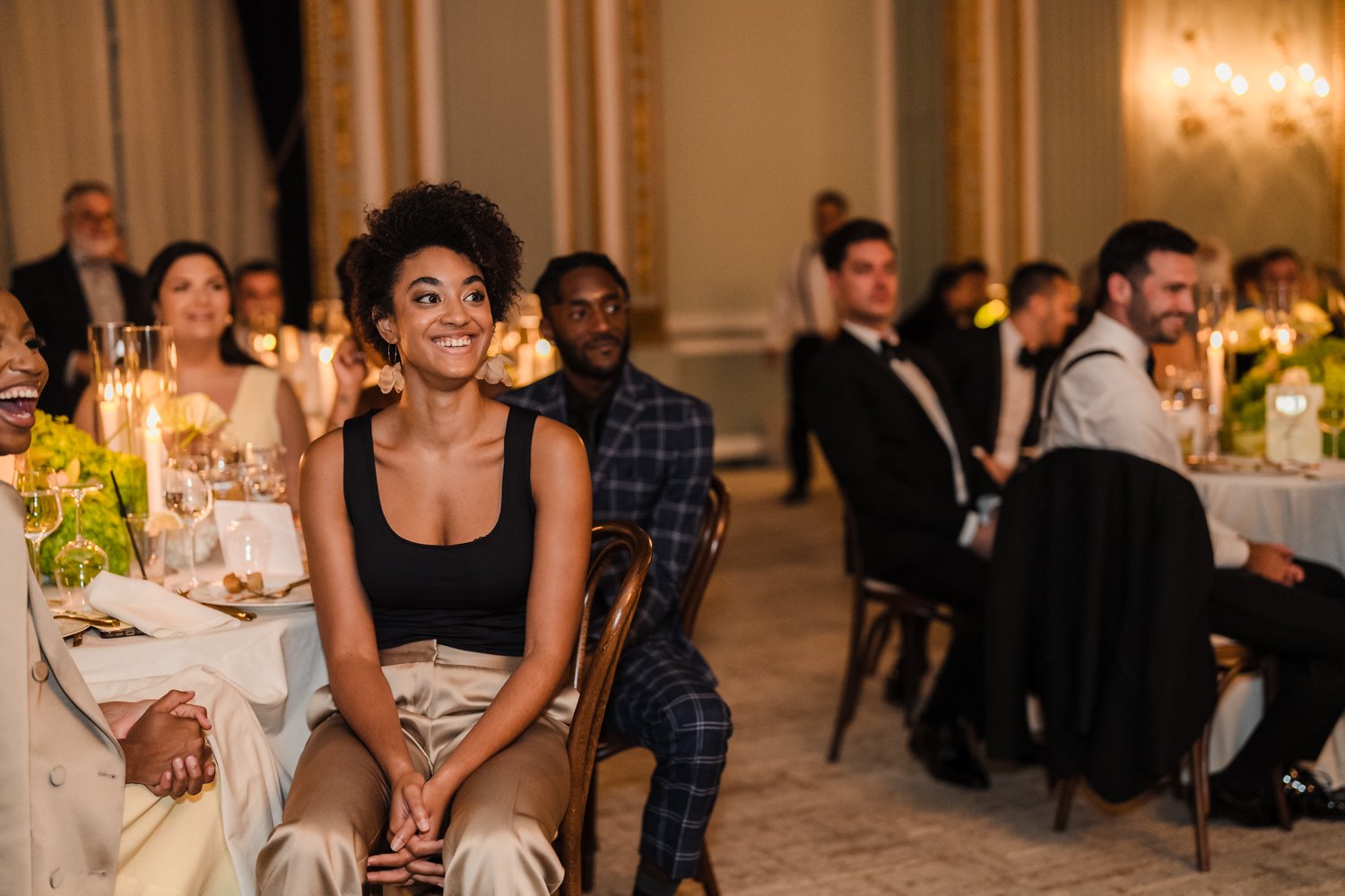 Wedding guests smiling and reacting during heartfelt speeches at an elegant reception.