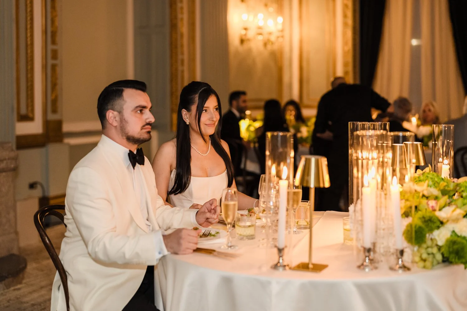 Bride and groom listening to heartfelt wedding speeches during their candlelit wedding reception at the Windsor in Montreal. 