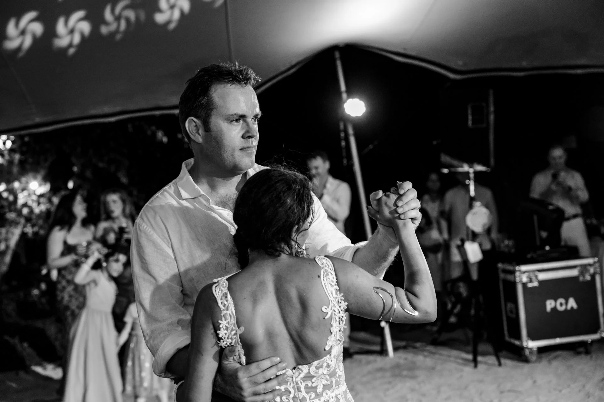 Documentary-style wedding photograph by Montreal wedding photographer Karishma Pageau. This black-and-white image captures the bride and groom sharing their first dance surrounded by family and friends, preserving an emotional and authentic moment fr