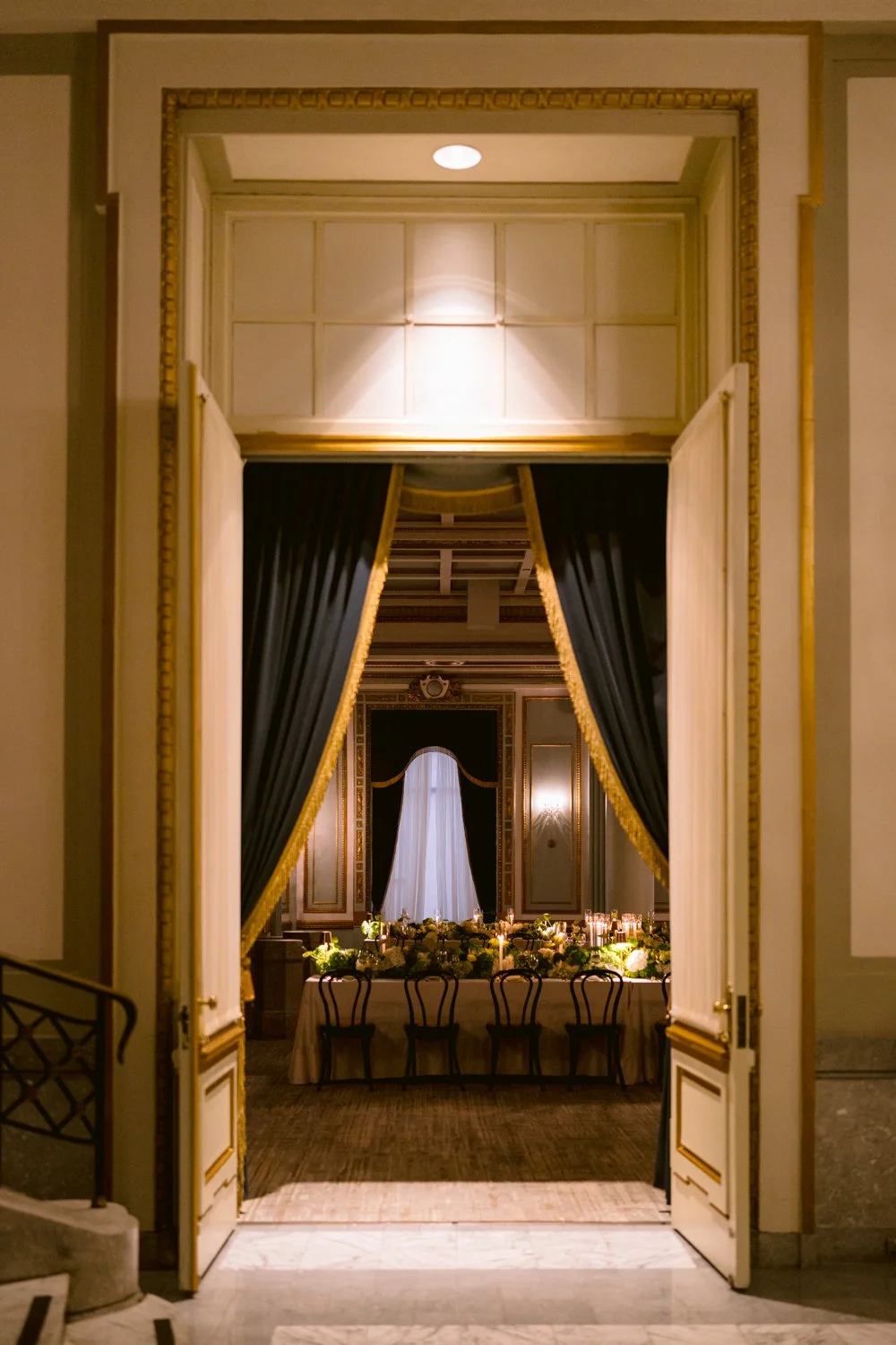 Elegant candlelit wedding reception room photographed through open doors at a Montreal wedding venue.
