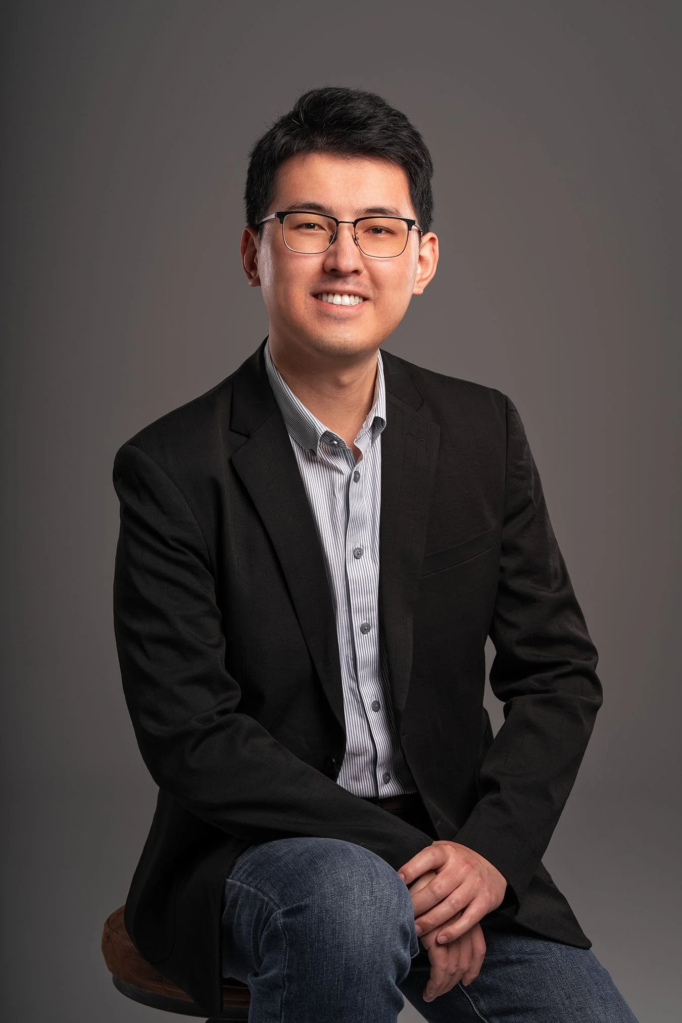 This professional headshot features a real estate agent in a sleek black blazer and striped shirt, exuding confidence and approachability. Captured against a clean, neutral background, he conveys a professional and trustworthy image, perfect for buil