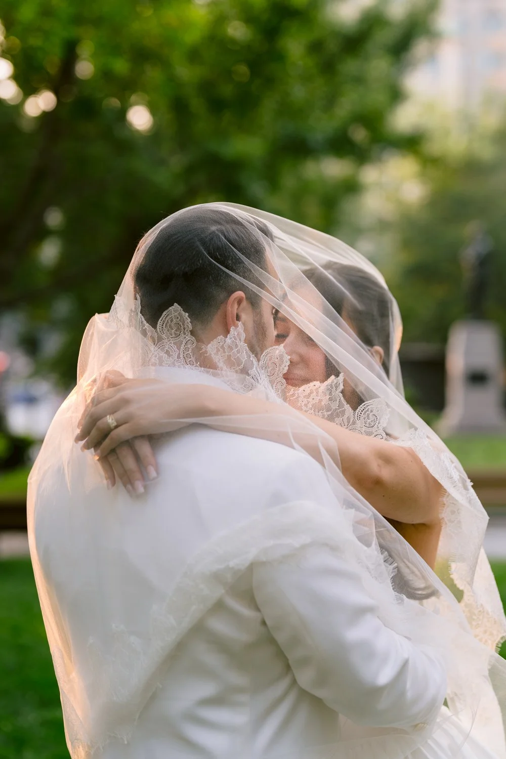 Bride and groom embrace beneath the bridal veil during romantic wedding portraits outside Le Windsor in Montreal.
