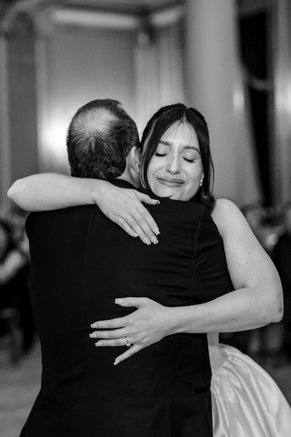 Bride embracing her father during an emotional moment at the wedding reception, at the end of their dance, photographed in a candid documentary style.