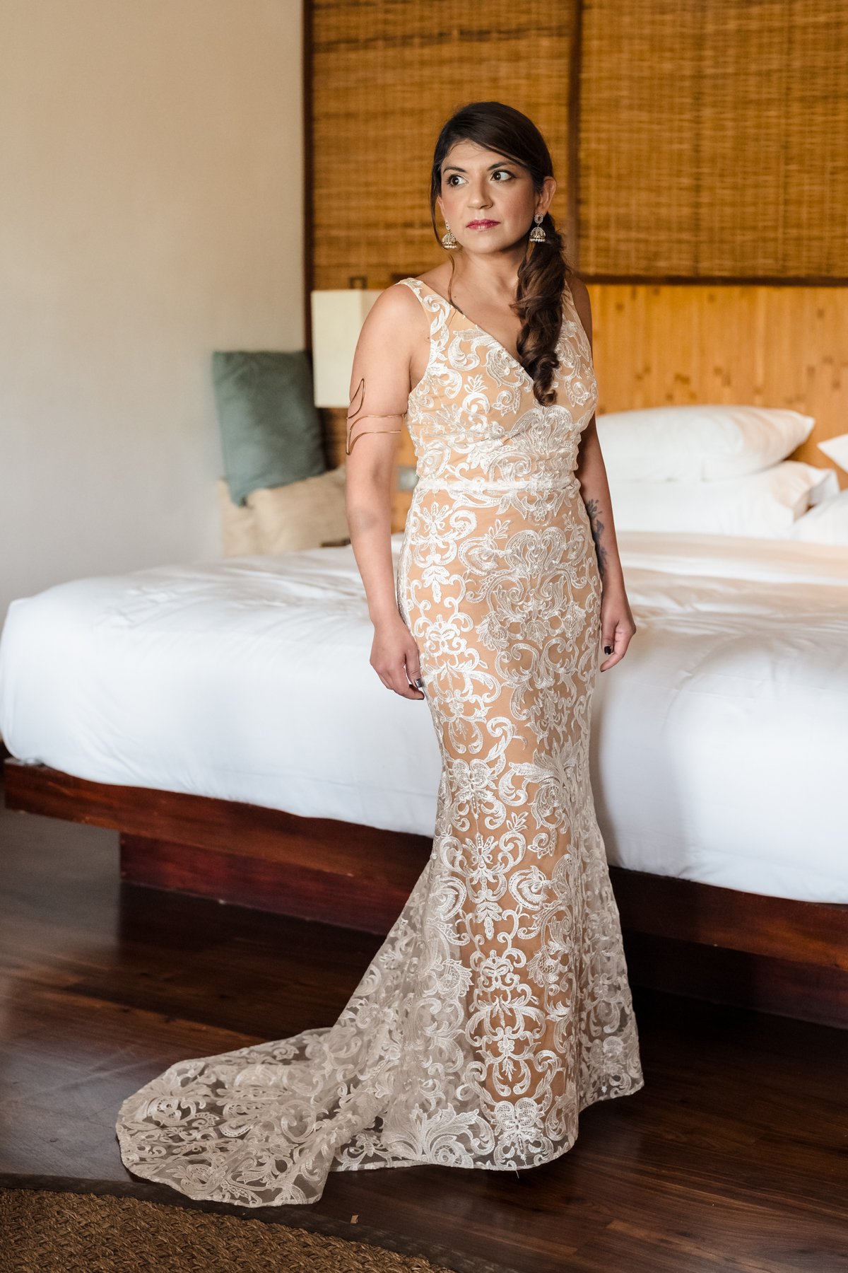 Bride in a lace wedding dress standing in a hotel room during wedding preparations in Mauritius.