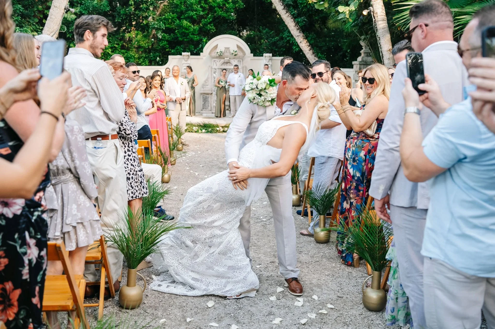 Newlyweds kiss while walking down the aisle after their Bonnet House Museum & Gardens wedding ceremony in Fort Lauderdale.