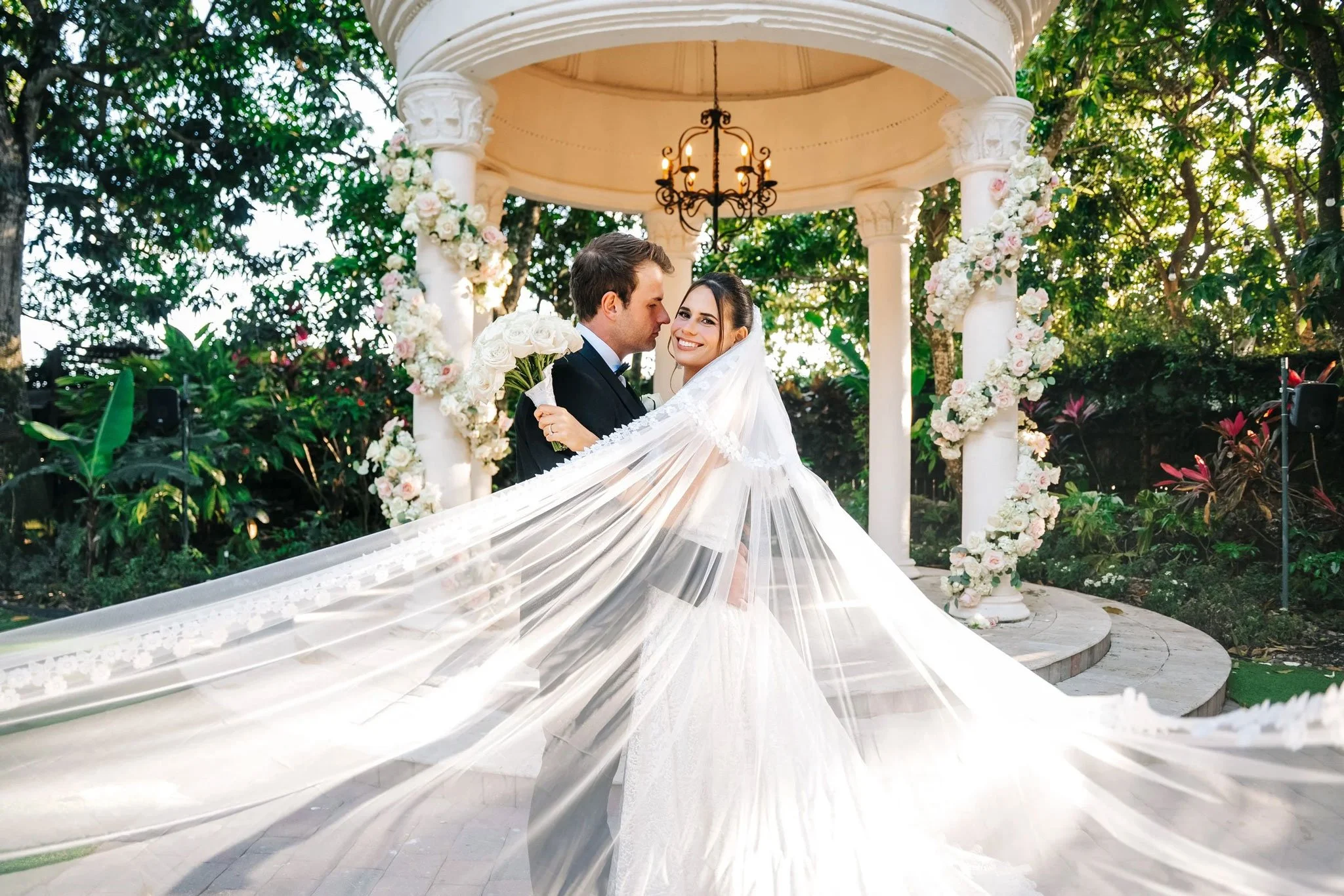 Bride and groom posing beneath a flower-decorated gazebo at Villa Toscana Miami