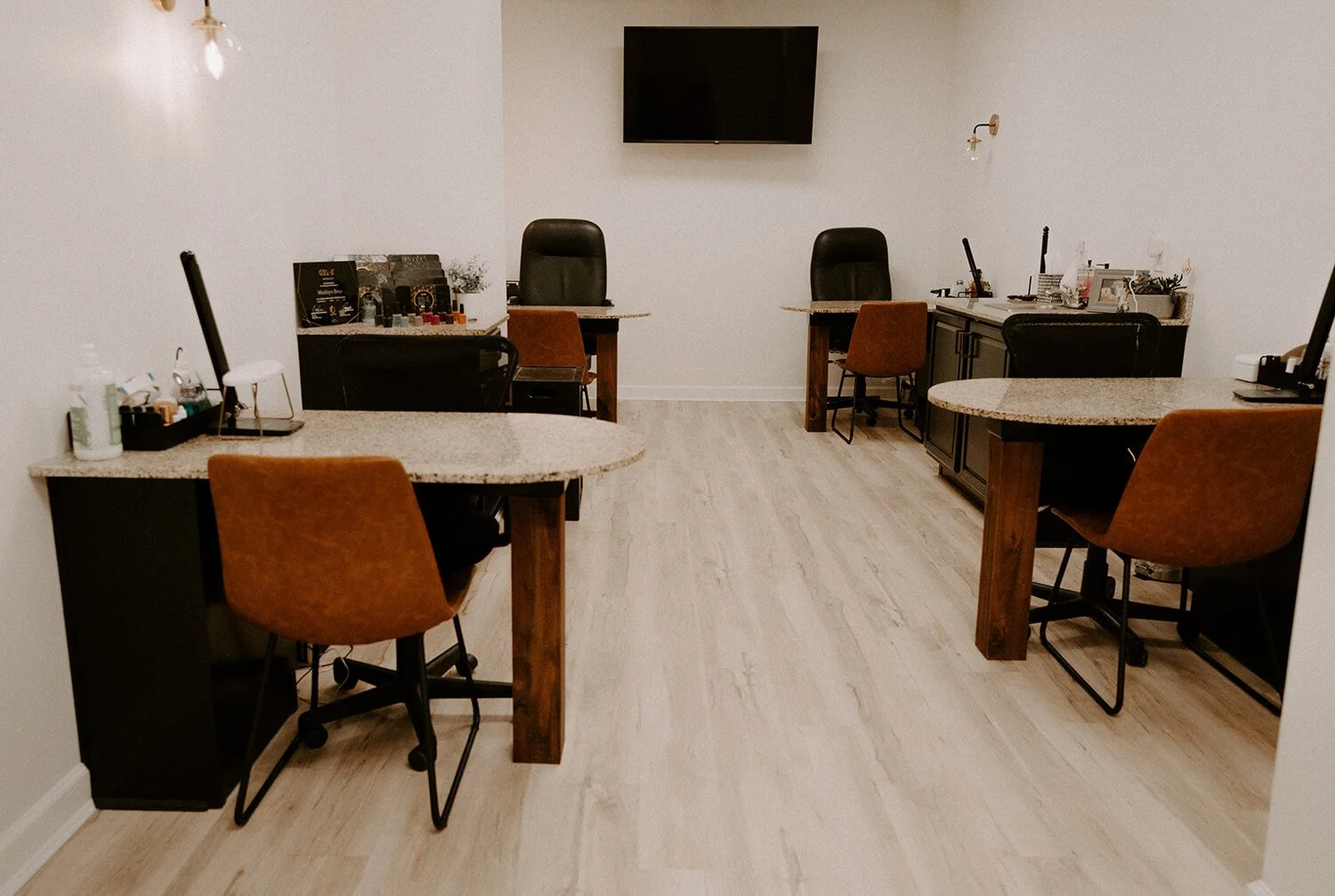 Manicure space with desks, white walls and wood flooring  at Salt + Light Salon and Spa in Cincinnati, OH