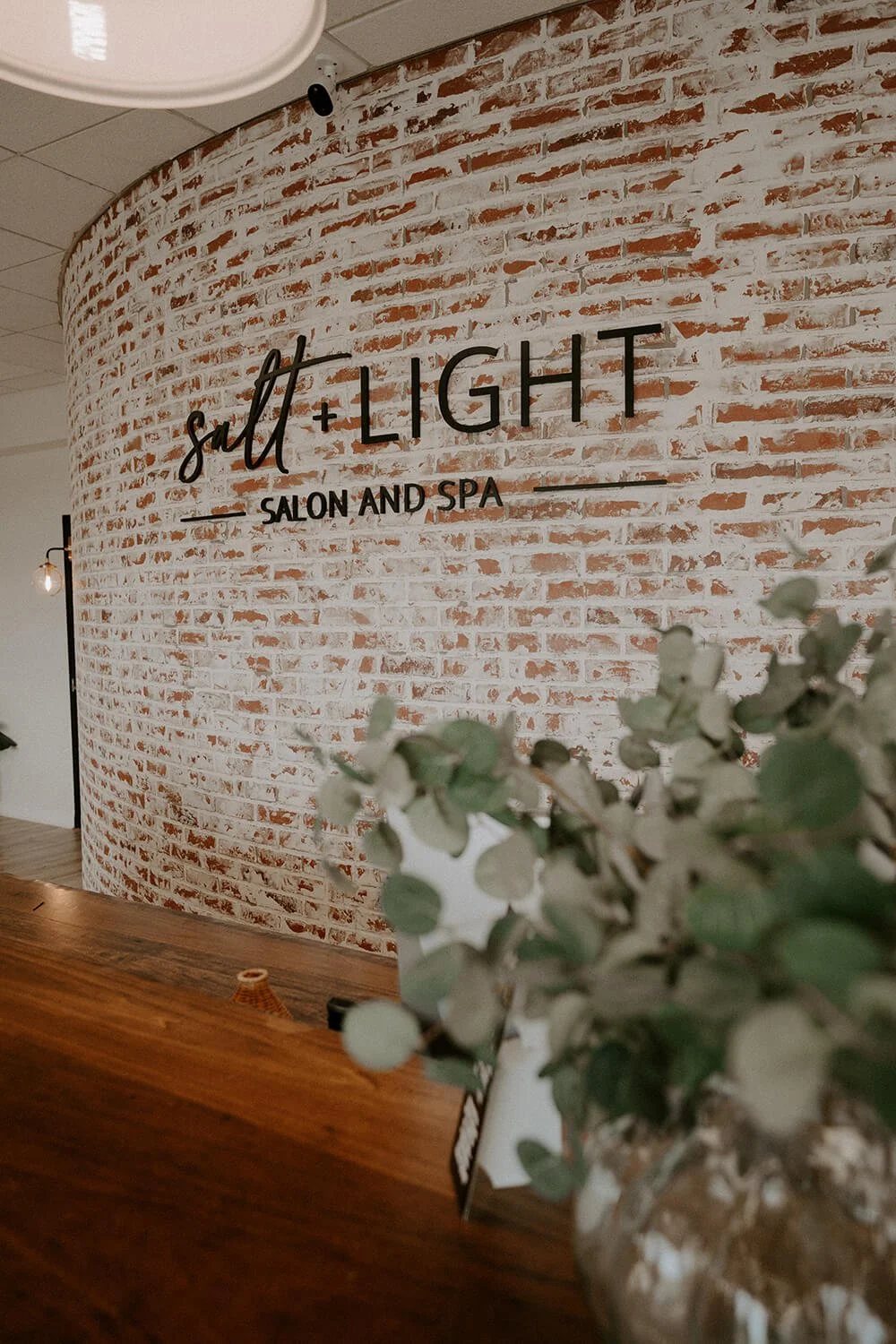 Front desk with a white brick curved wall  at Salt + Light Salon and Spa in Cincinnati, OH