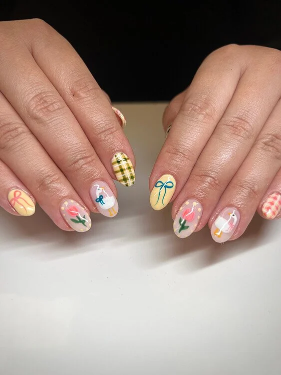Custom nail art featuring Christmas-themed designs such as ribbons, holly, a gift box, a reindeer, and plaid patterns done at Salt + Light Salon and Spa in Cincinnati, OH