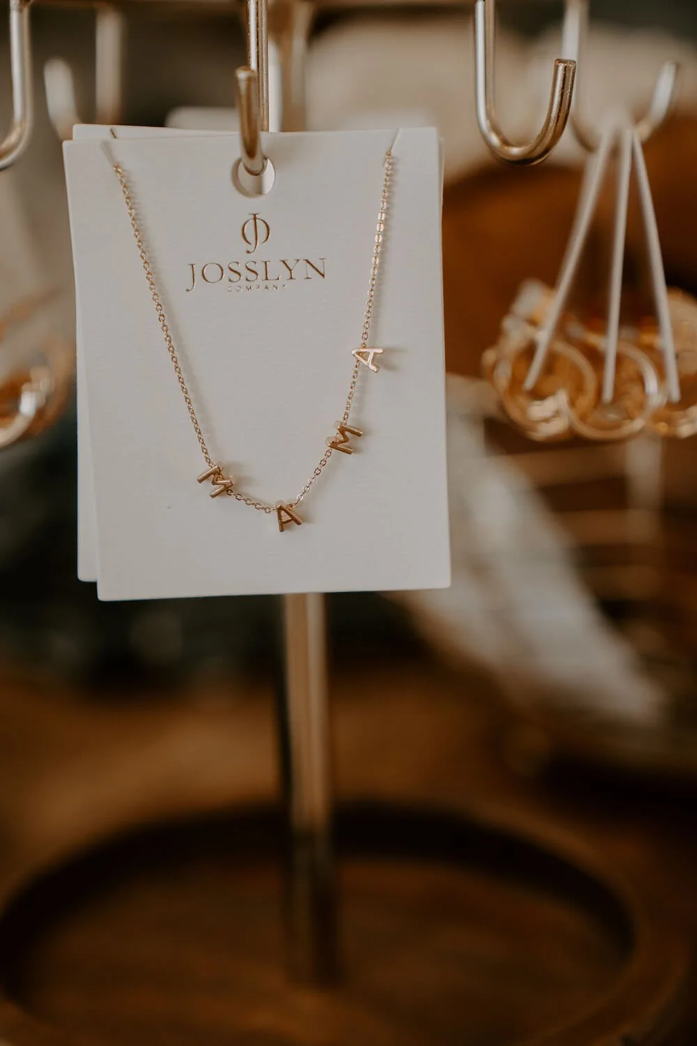 Gold necklace with letter charms spelling 'AMAZING' hanging on a display card at the Shop Salt boutique.