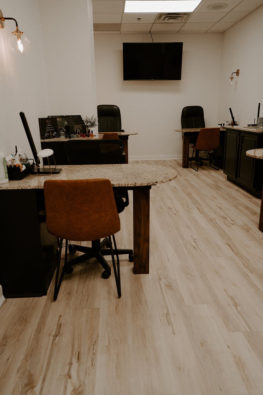 Manicure space with desks, chairs, and a wall-mounted TV  at Salt + Light Salon and Spa in Cincinnati, OH