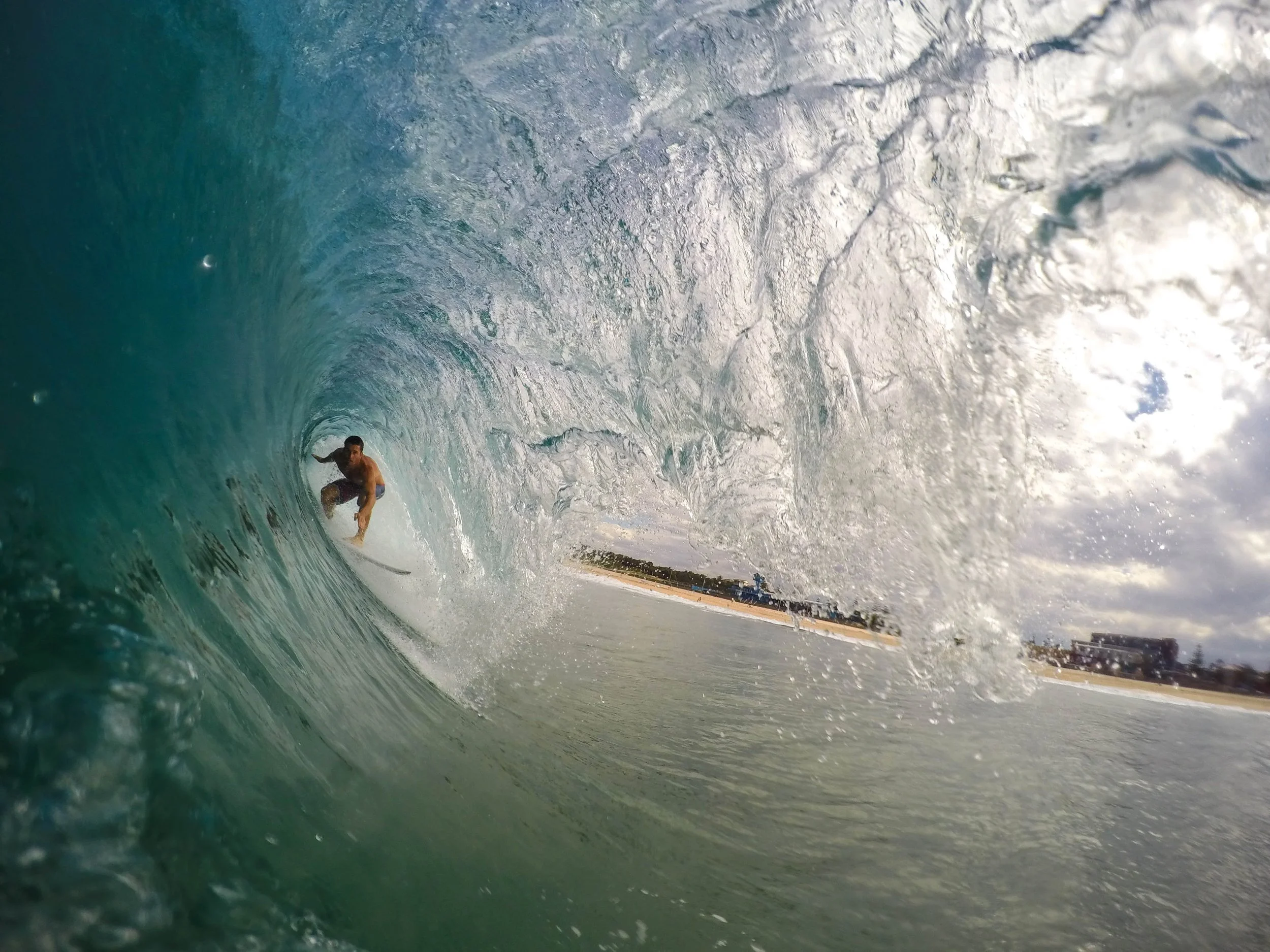 Young man rides in the center of a large wave on a surfboard