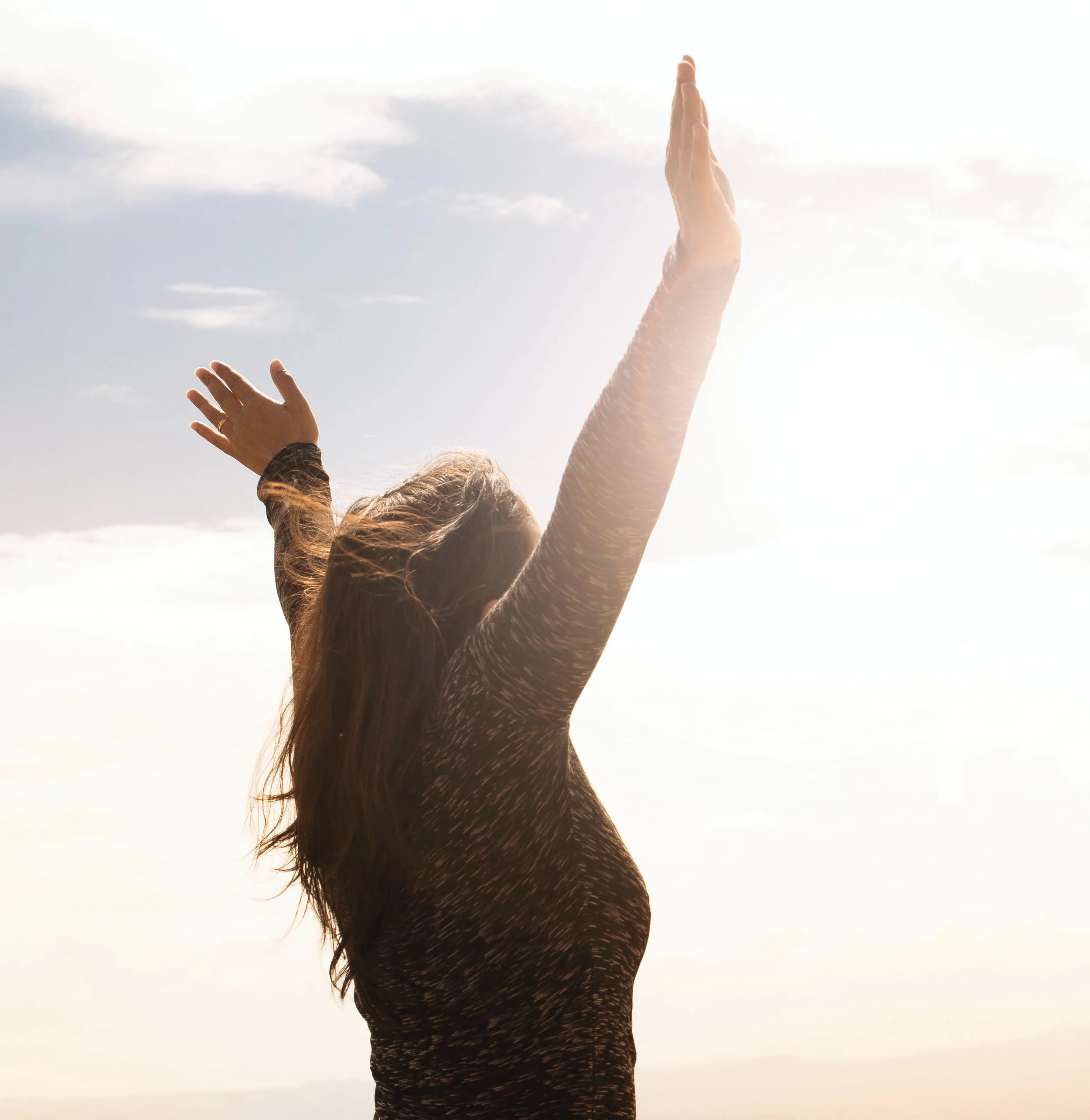 Woman embraces her freedom holding up her hands to the sky, looking very free and happy