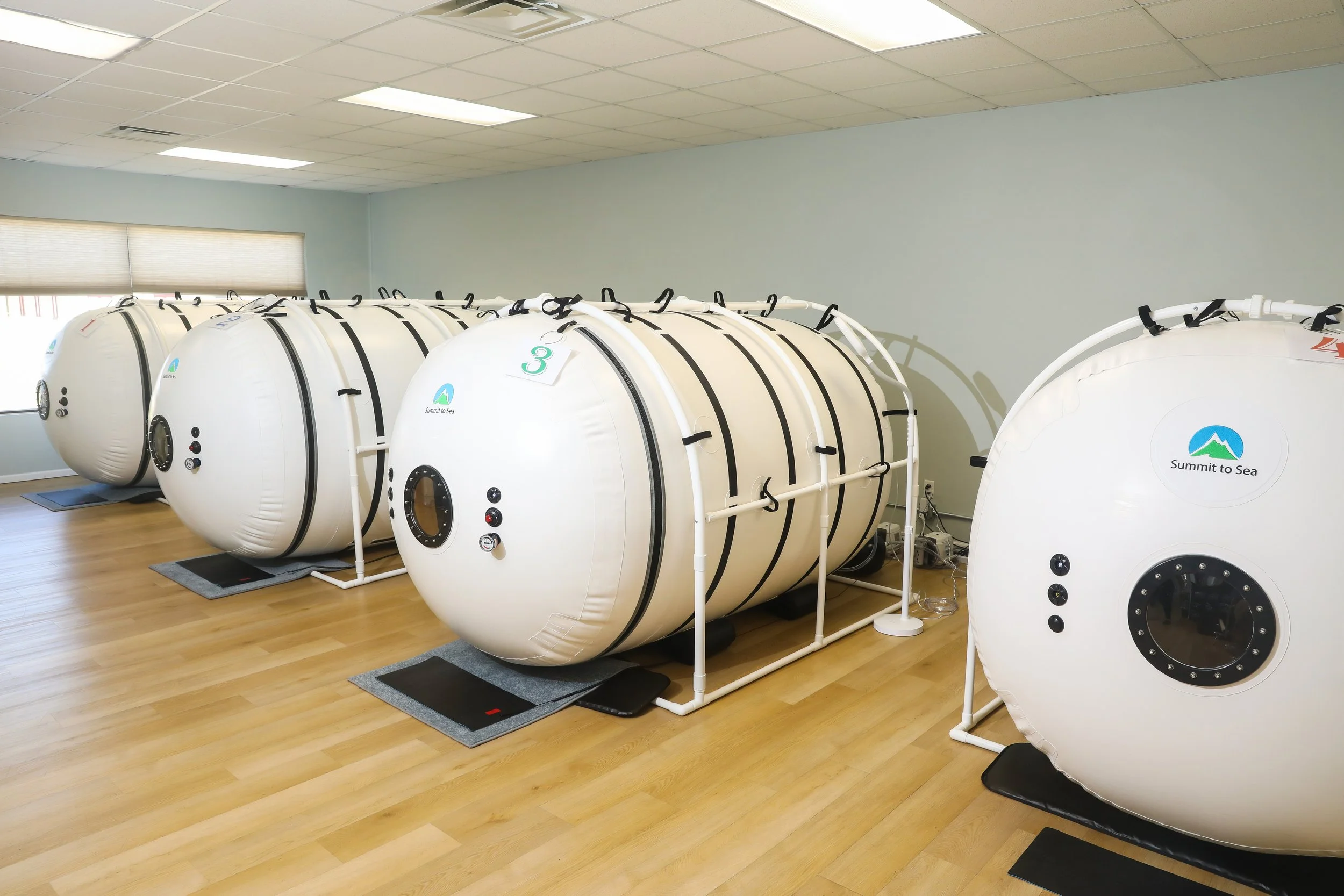 Room with multiple white hyperbaric oxygen chambers (HBOT)