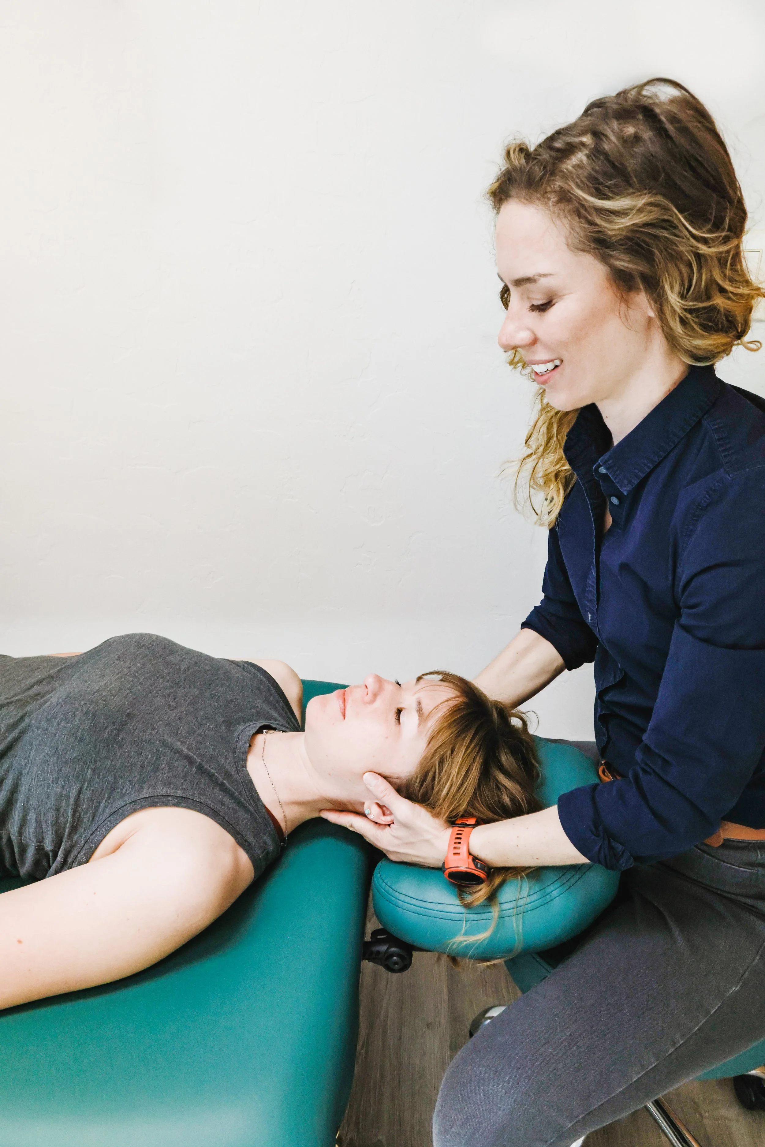 A physical therapist working on a patient's neck inside a clinic.