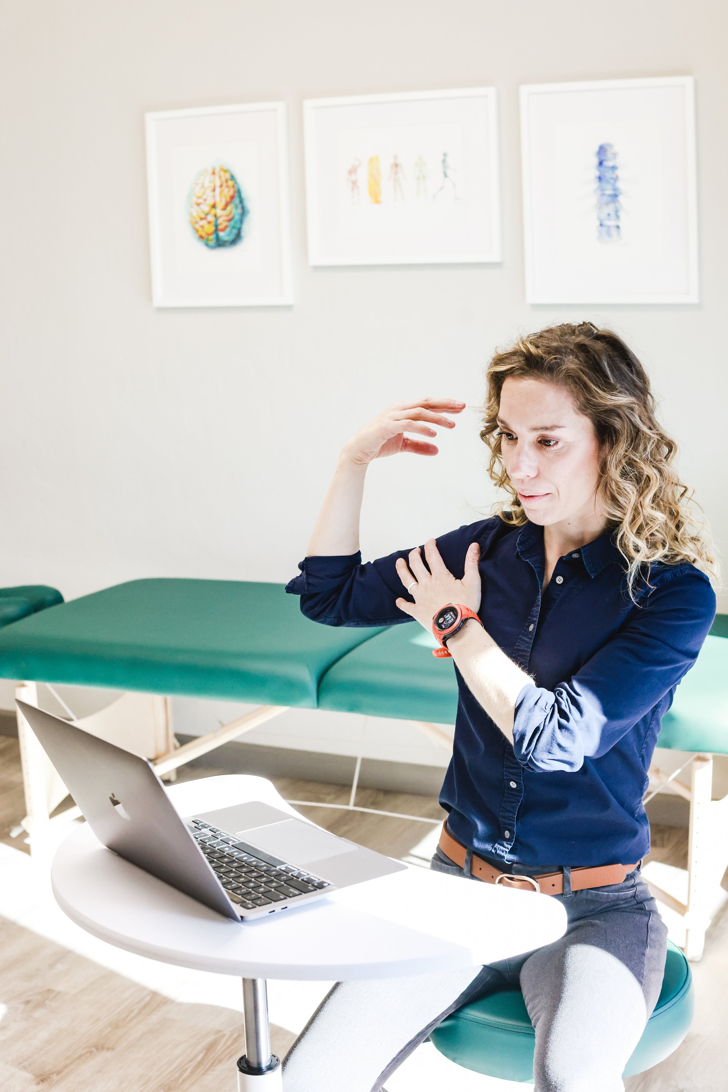 Physical therapist coaching another physical therapist on a laptop.
