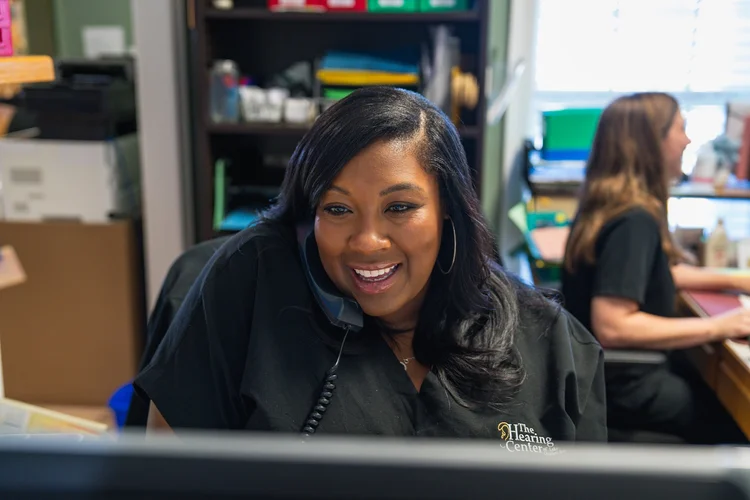 Smiling team member at her desk during an on-site branding shoot at The Hearing Center in Lake Charles