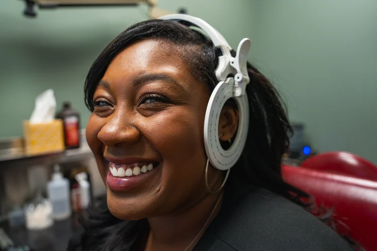 Smiling woman wearing white headphones during a hearing test at an audiology clinic, healthcare branding photo, Lake Charles