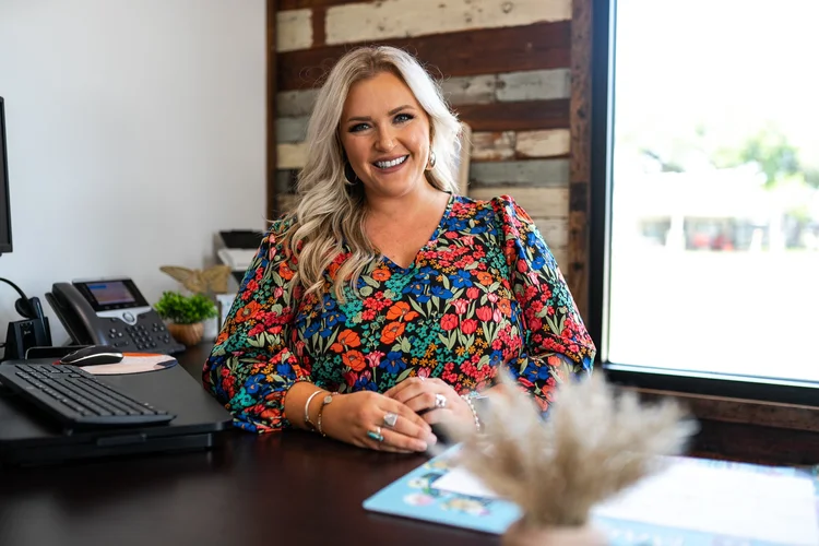 Smiling business owner in a floral top at her office desk, personal branding photo in Lake Charles