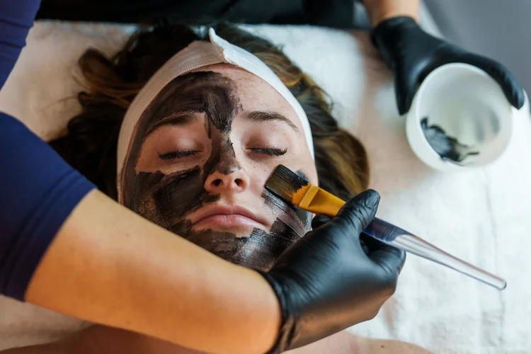 Esthetician brushing a facial mask onto a client, Lake Charles spa branding photography