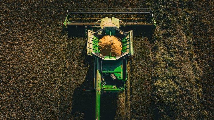 Aerial drone view looking straight down on a green combine harvester with a full grain hopper cutting a field, agriculture branding photo, Lake Charles