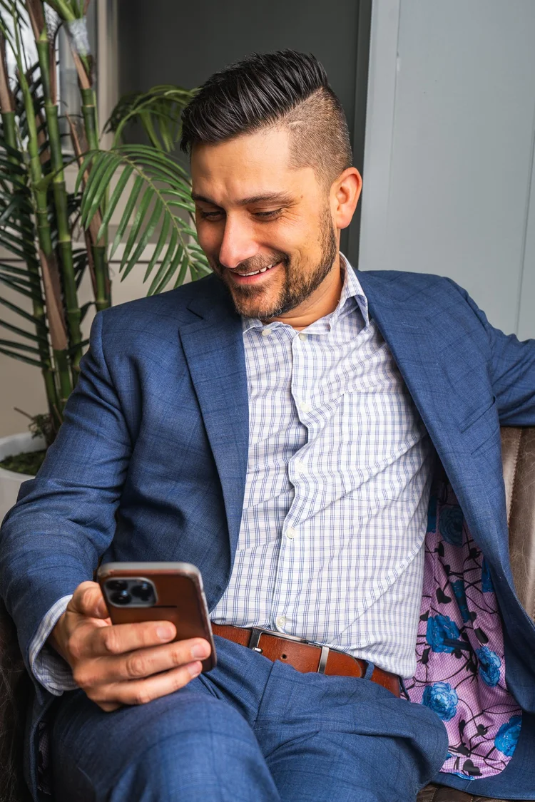 Businessman in a blue suit checking his phone in a modern office lounge, branding photography in Lake Charles