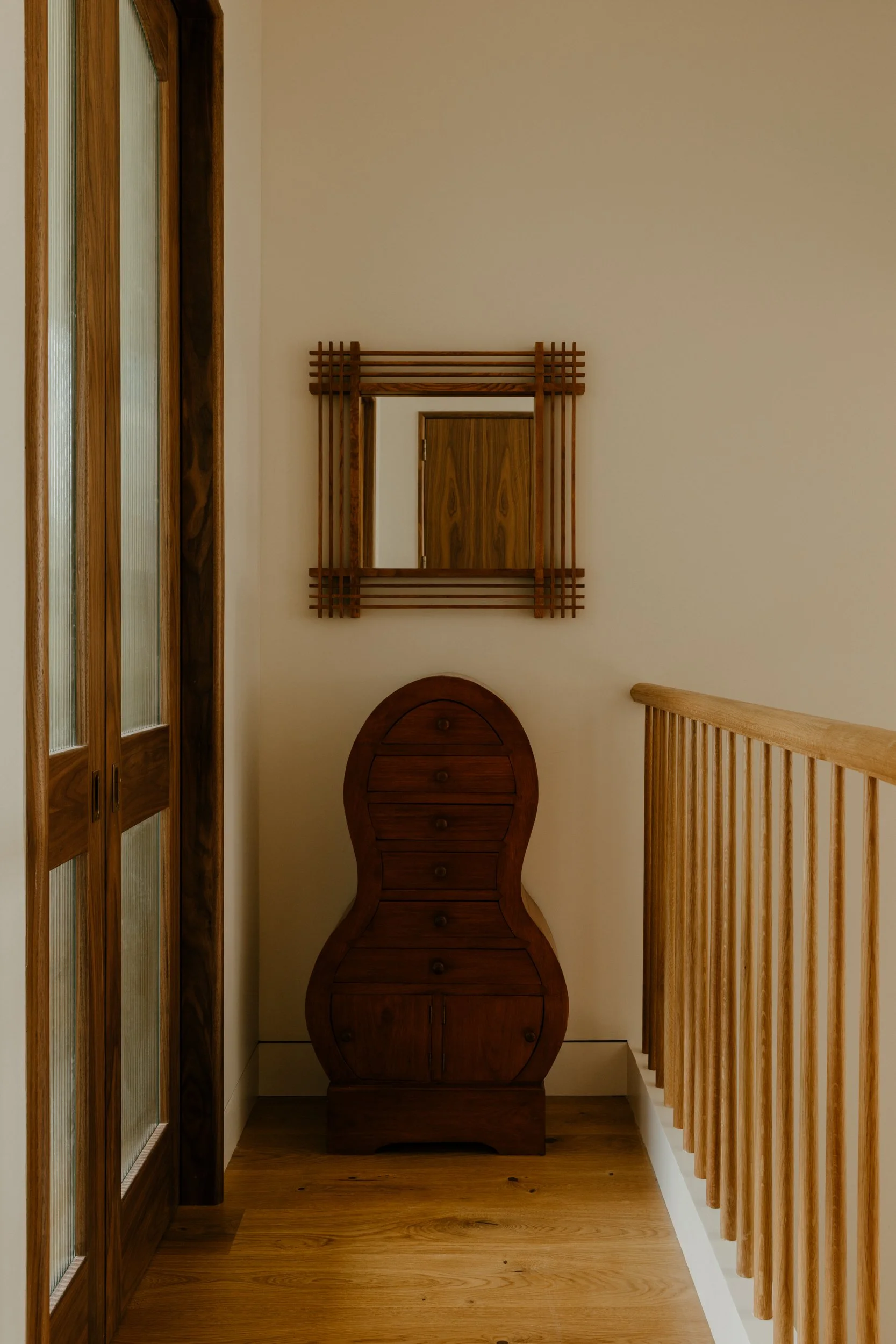 The 3rd floor landing punctuated with vintage finds from auctions next to custom designed glass and walnut doors to the playroom help bring light into the 3rd floor hallway