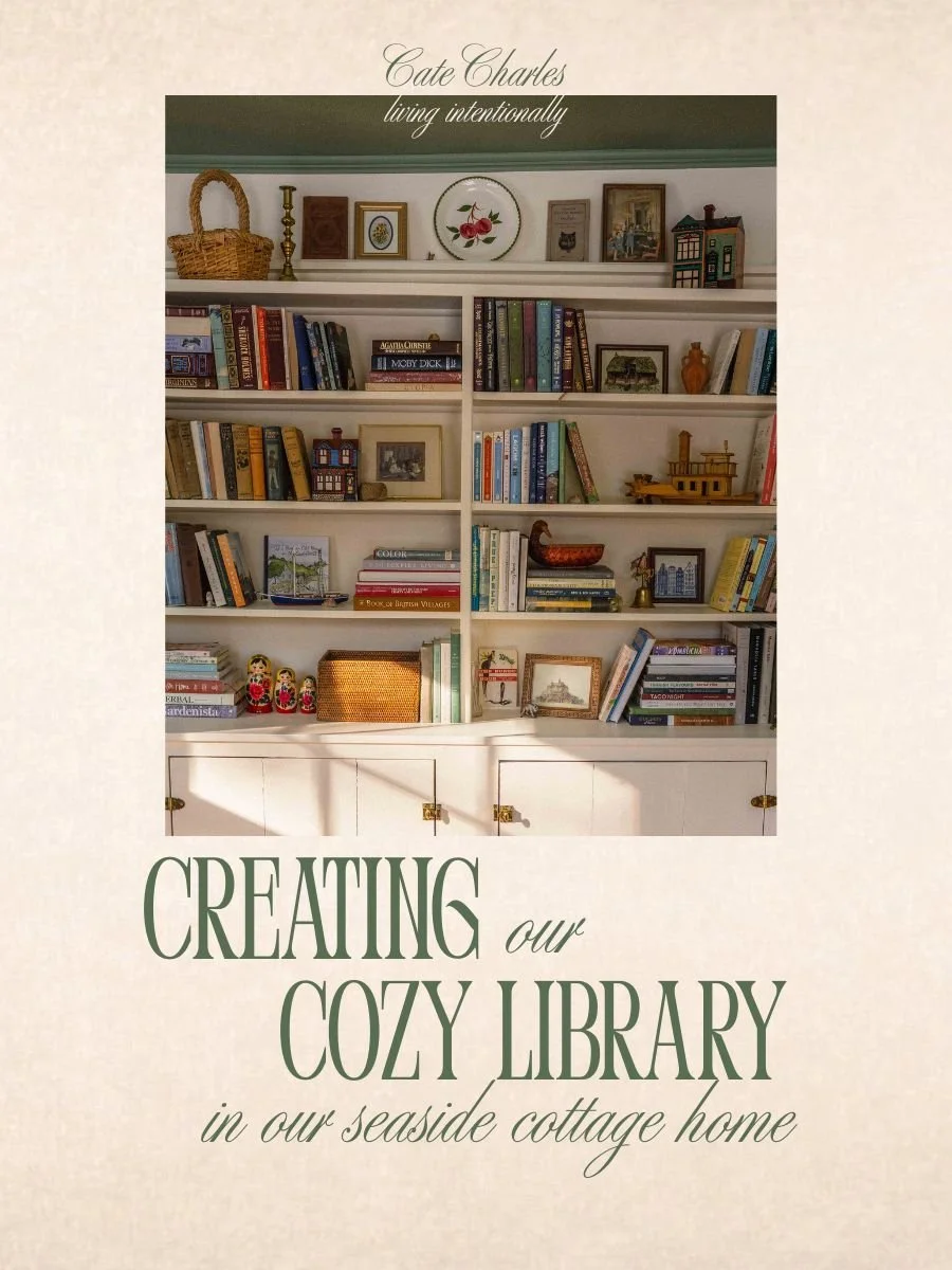 inlayed image is of a cream built in bookshelf styled with colourful books, antiques and baskets in a cottagecore home library. Text overlay reads "creating our cozy library in our seaside cottage home"