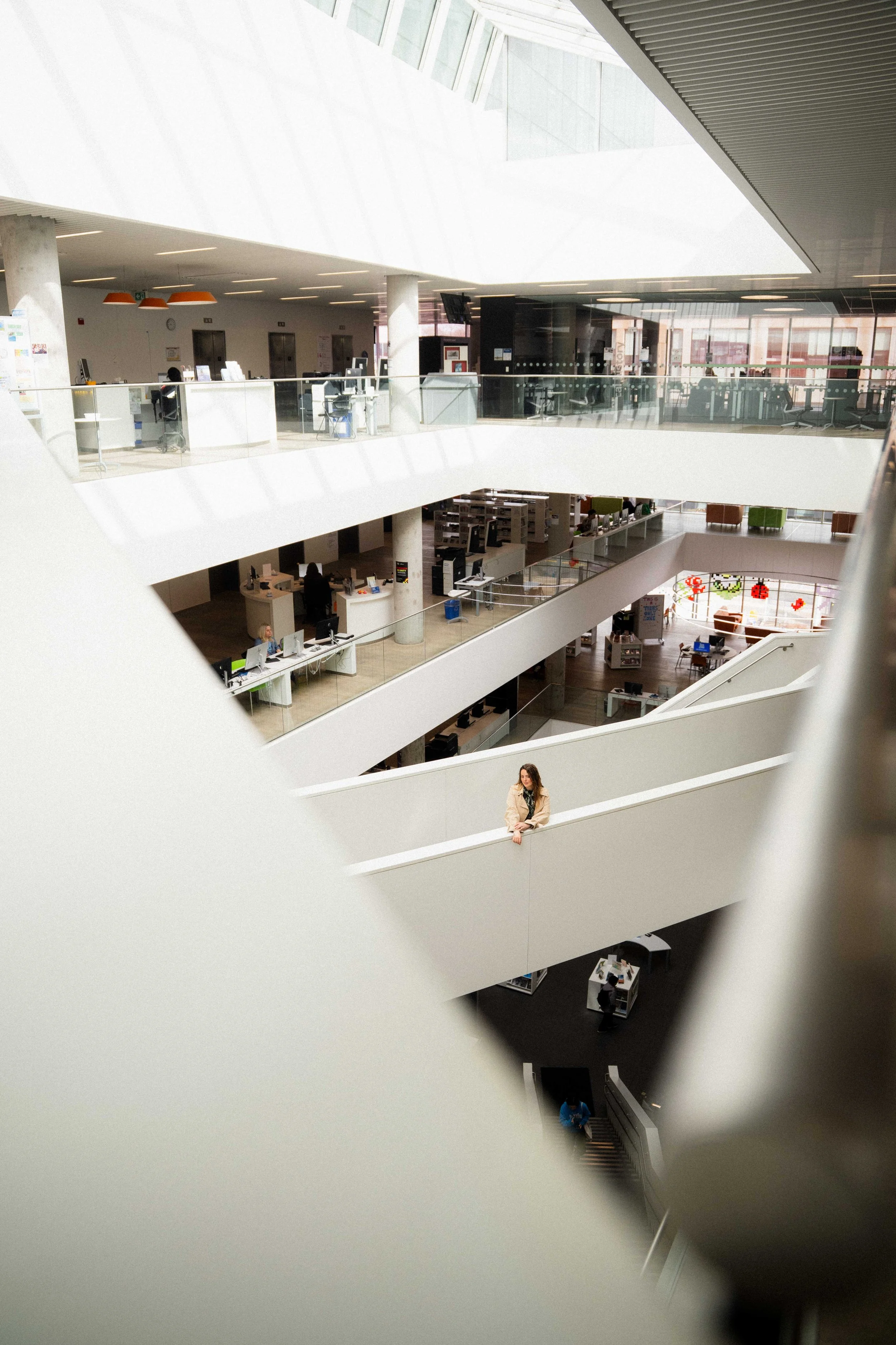 exploring Halifax Third Spaces in the Central Library, a modern building with tons of natural lighting, a girl is standing iin the middle of an interior bridge